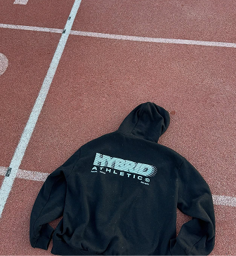 Black hoodie with blue and white logo lying on a red sports track