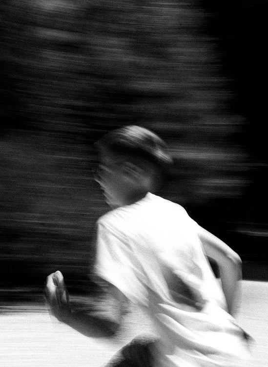 A young boy running outdoors, blurred motion showing speed.
