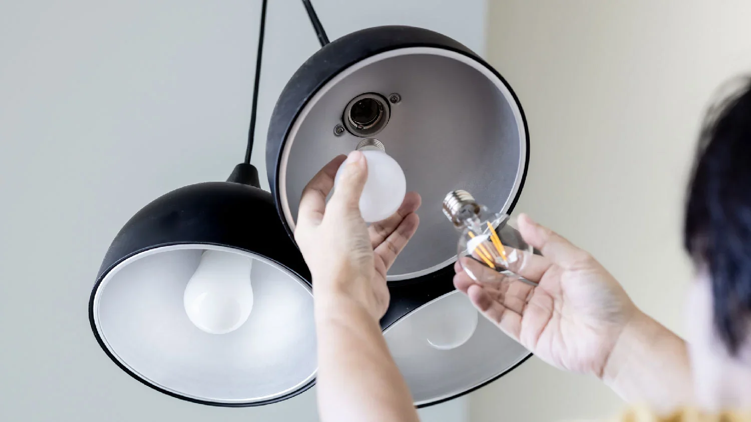 Person replacing a light bulb in a ceiling light fixture.