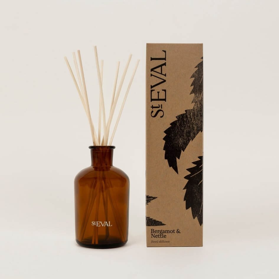 Amber glass bottle of St. Eval Bergamot & Nettle Reed Diffuser with natural reeds, shown beside kraft box packaging with black botanical print