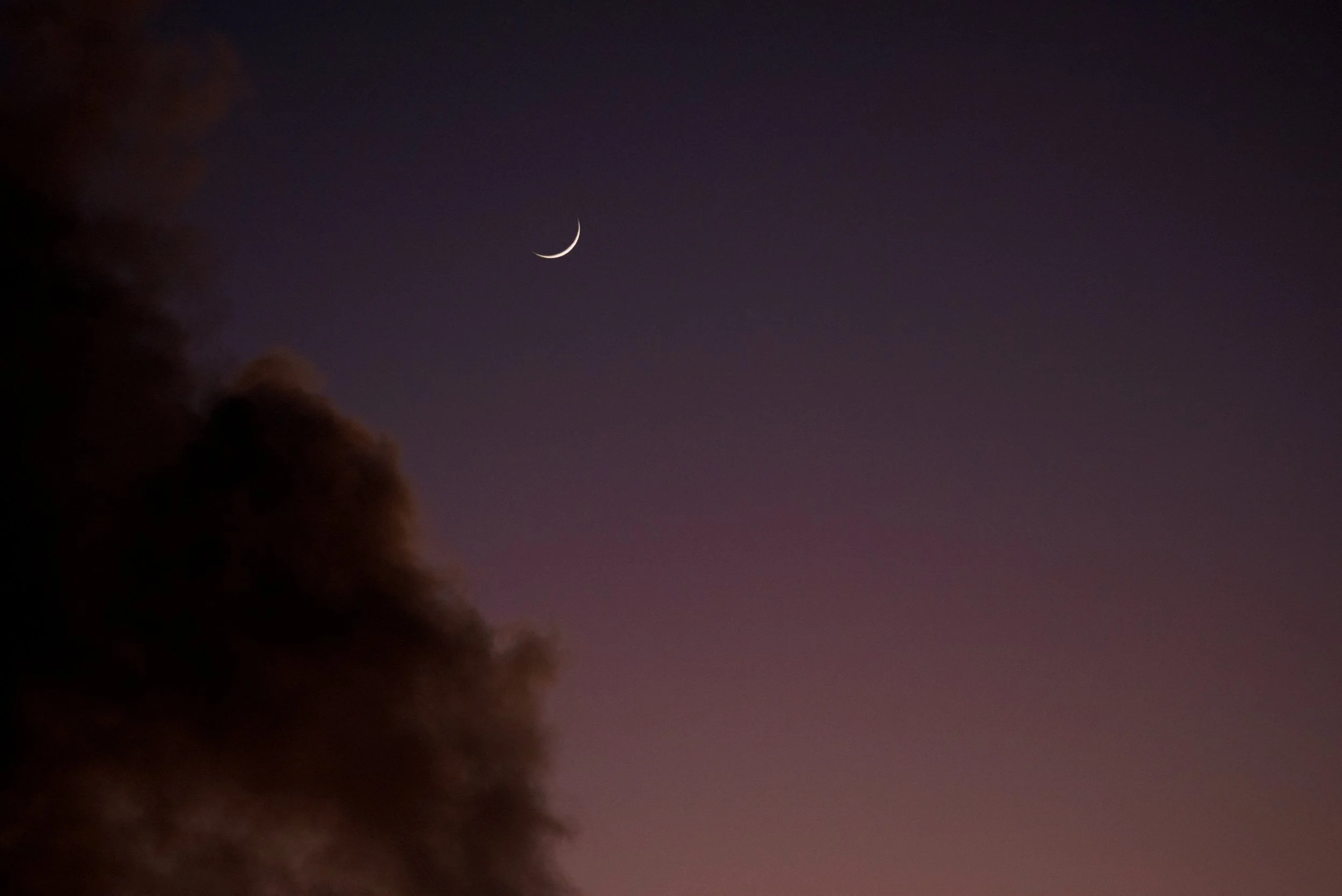 Night sky with a crescent moon and some clouds on the left side.