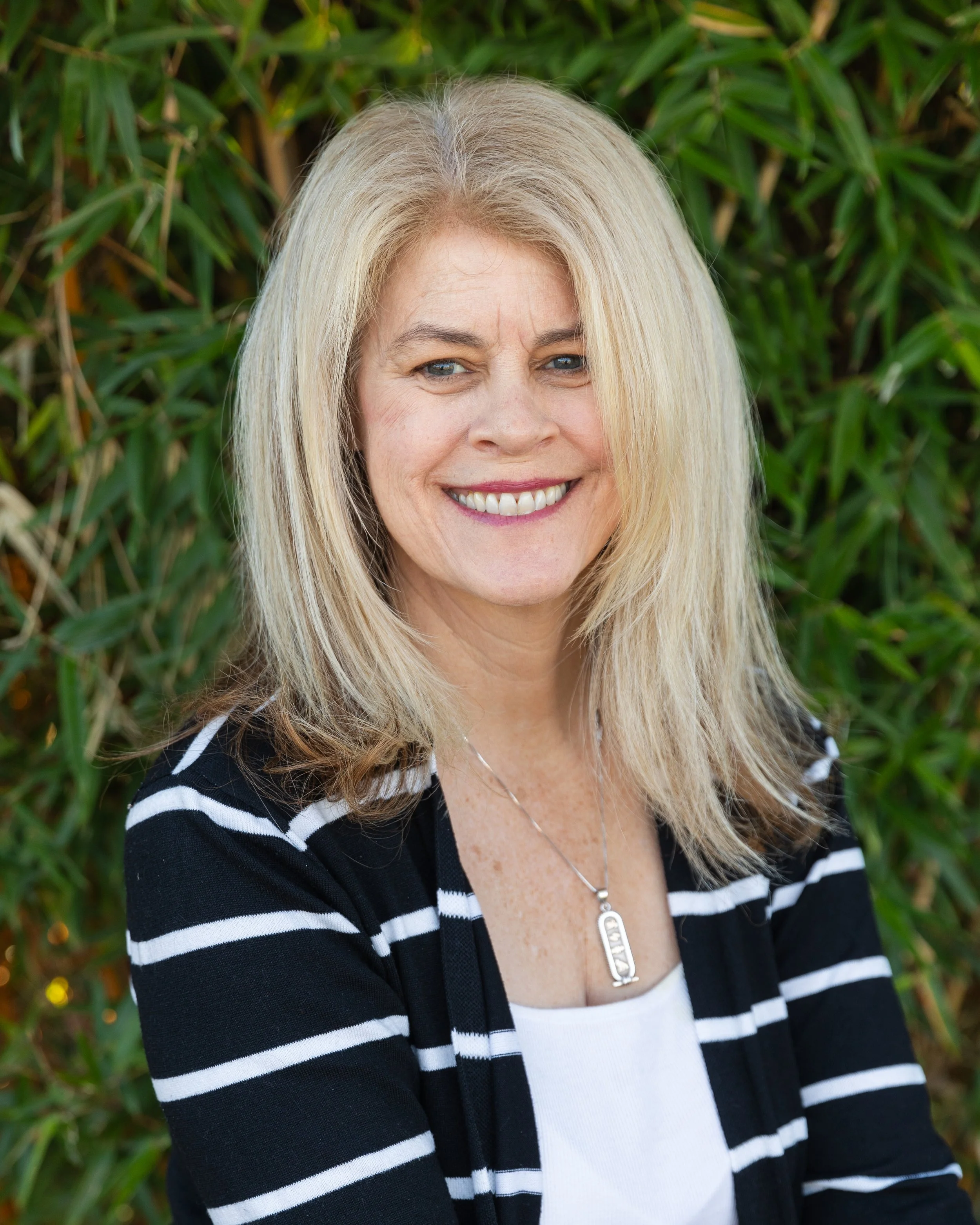 Lisa Omar, Director of Advancement, smiling in front of foliage