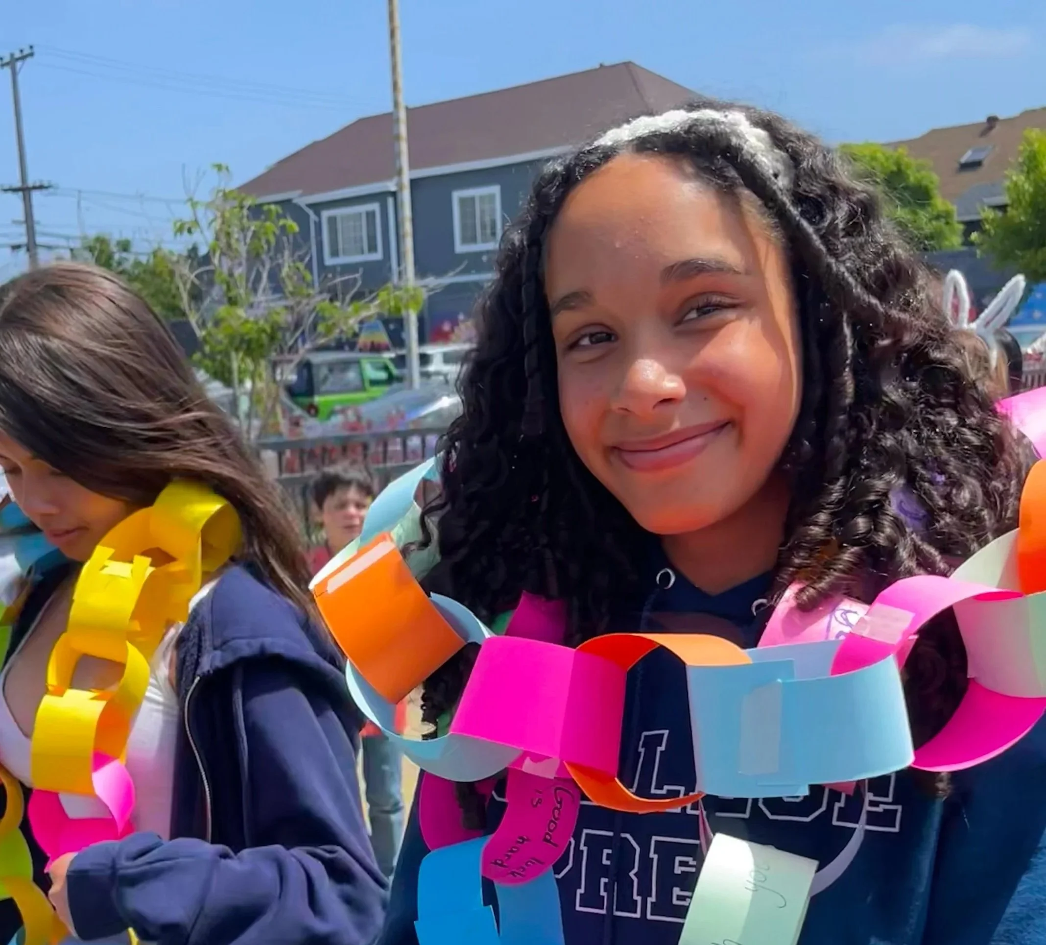 Smiling girl with paper daisy chain draped on her shoulders