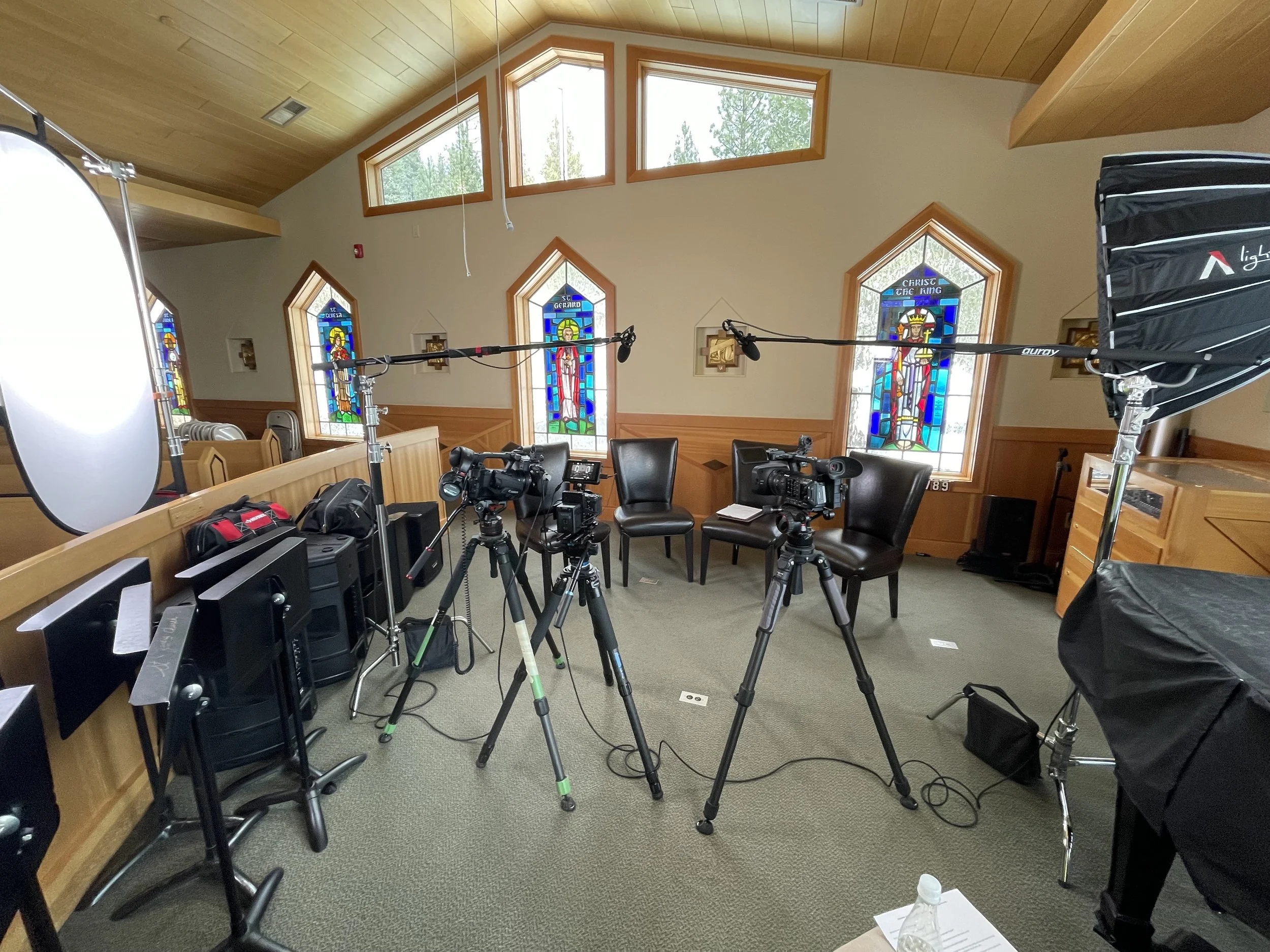 Video equipment in a church with stained glass windows behind.