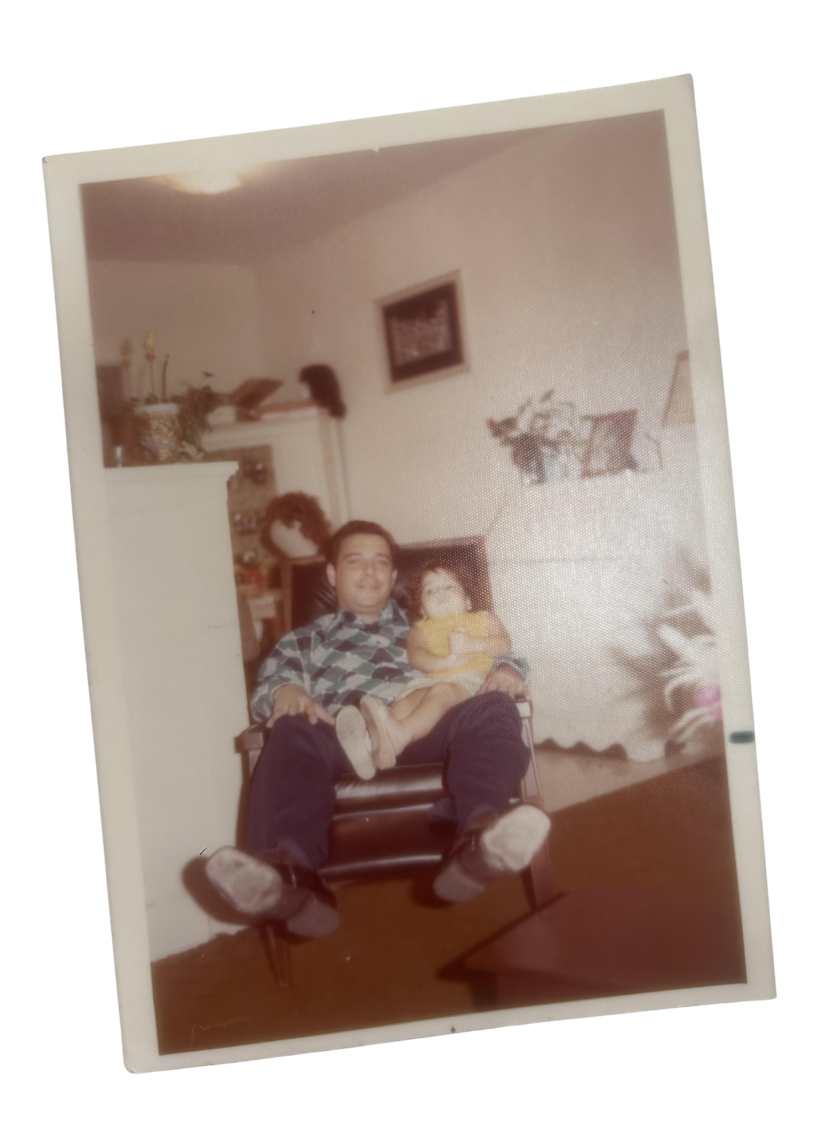 Young Krystal Fernandez sits on her father’s lap in a cozy living room, wearing a yellow dress. This heartfelt moment reflects the family bond that inspired The Nenita Foundation’s mission to support children and families in need.