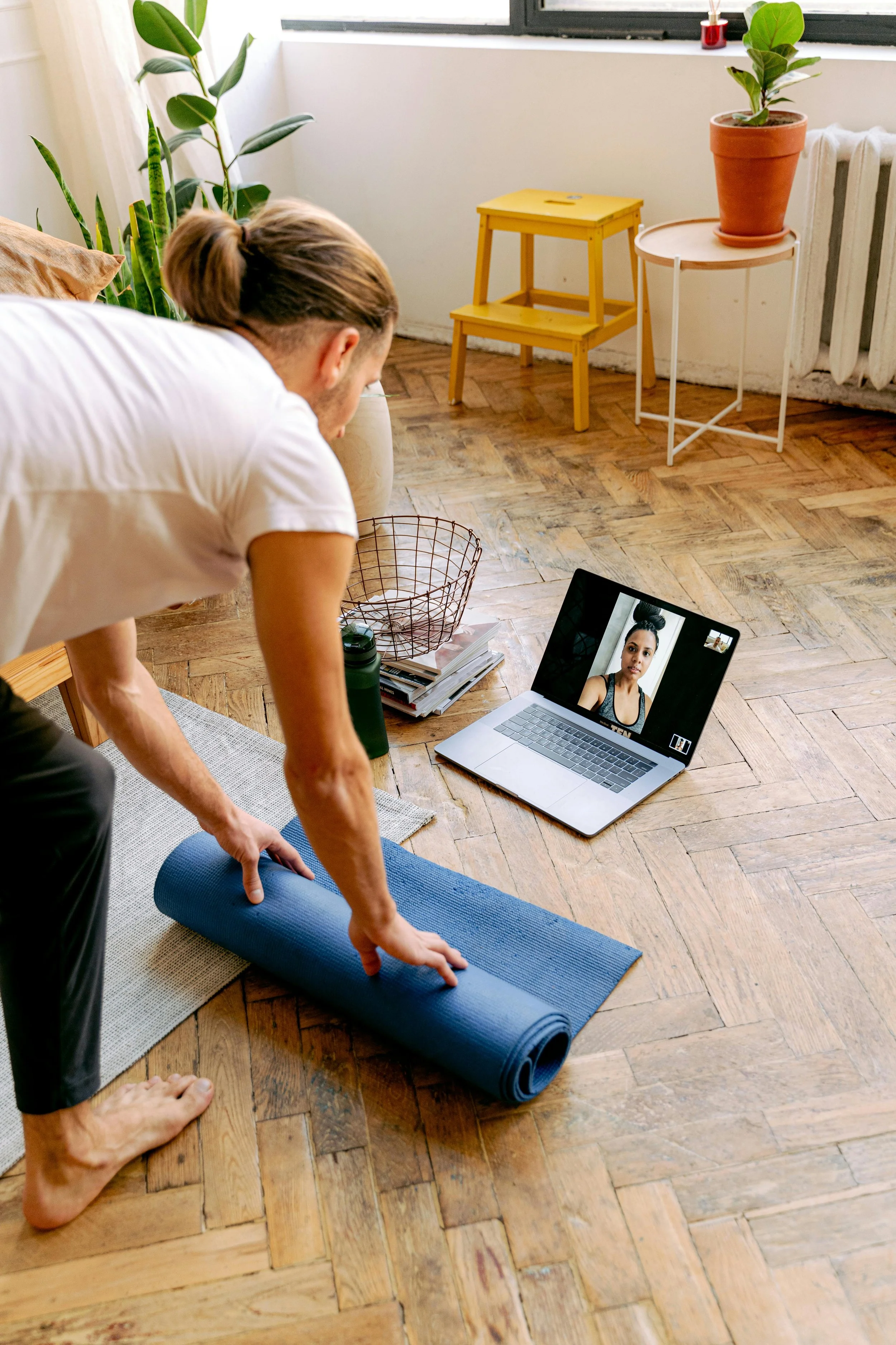 Person doing yoga in a living room during a video call on a laptop.