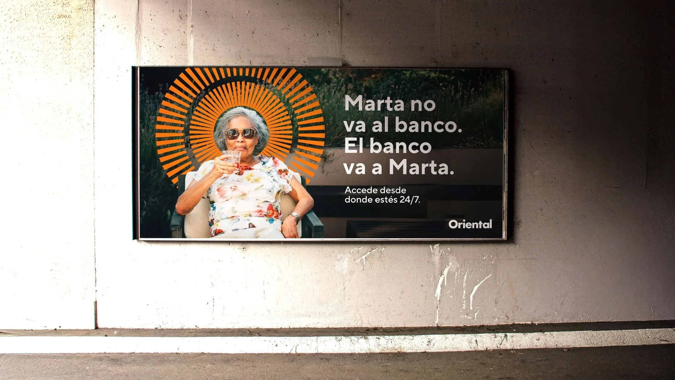 An elderly woman with sunglasses sitting outside, holding a glass, with an orange sunburst graphic behind her head. Spanish text promoting bank access for Marta.