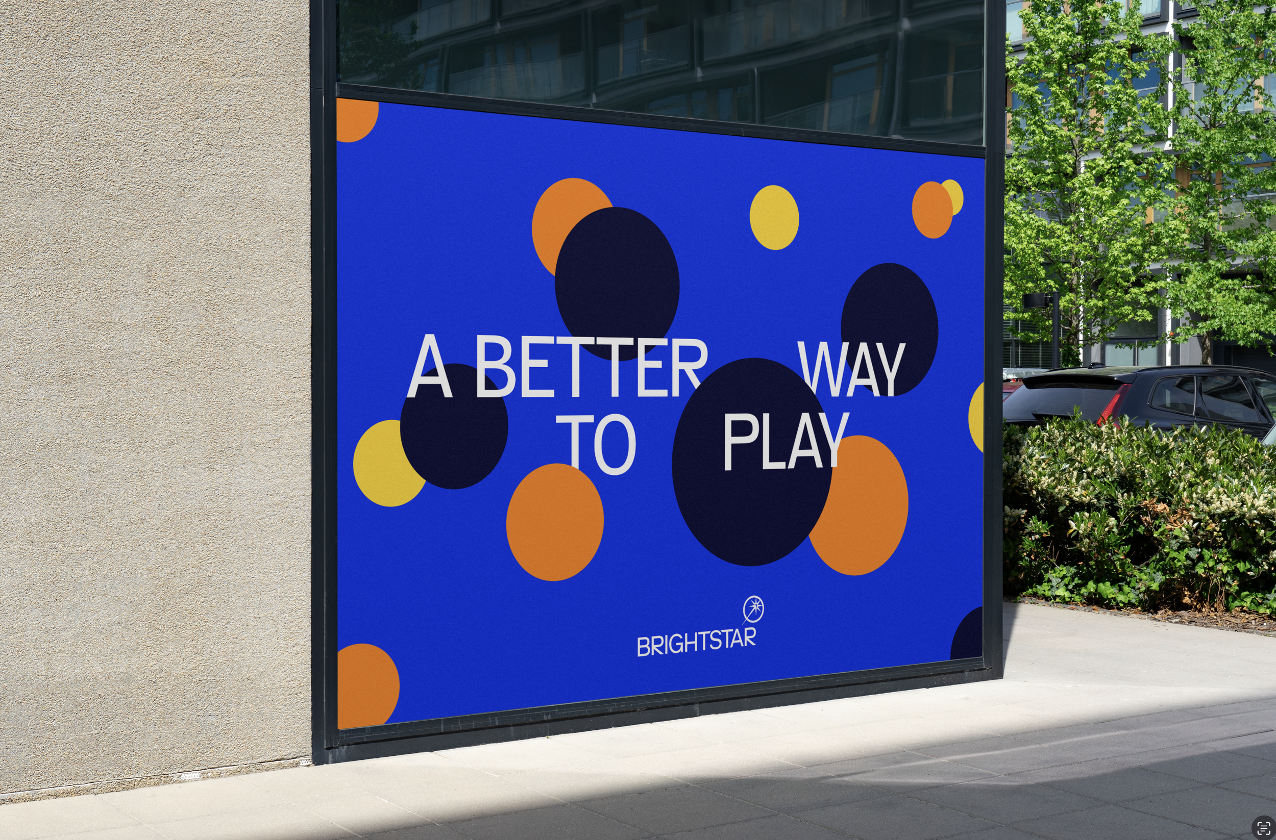Outdoor advertisement poster with a blue background, featuring scattered black, yellow, and orange circles, and white text that reads "A BETTER WAY TO PLAY" and the logo for Brightstar at the bottom.
