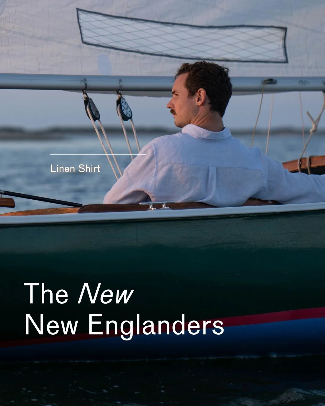 A man in a white linen shirt sailing a boat on the water at sunset.