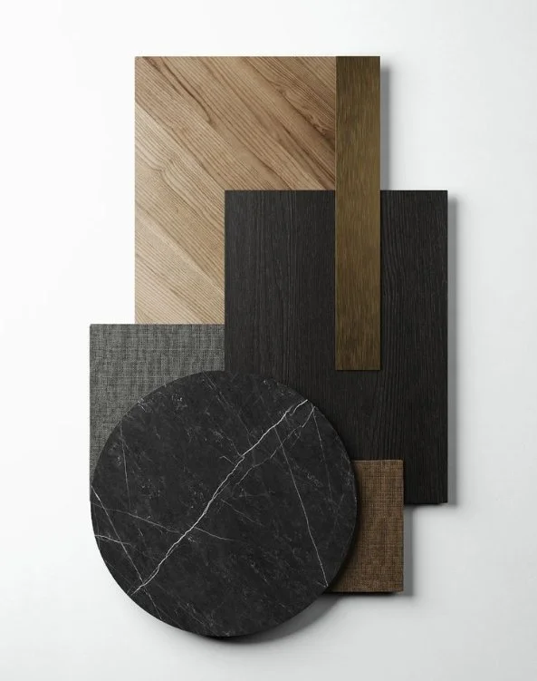 A collection of six different wood and stone samples arranged on a white background, including two rectangular wood pieces, a round black marble piece, a small square brown piece, a textured gray piece, and a long narrow dark wood piece.