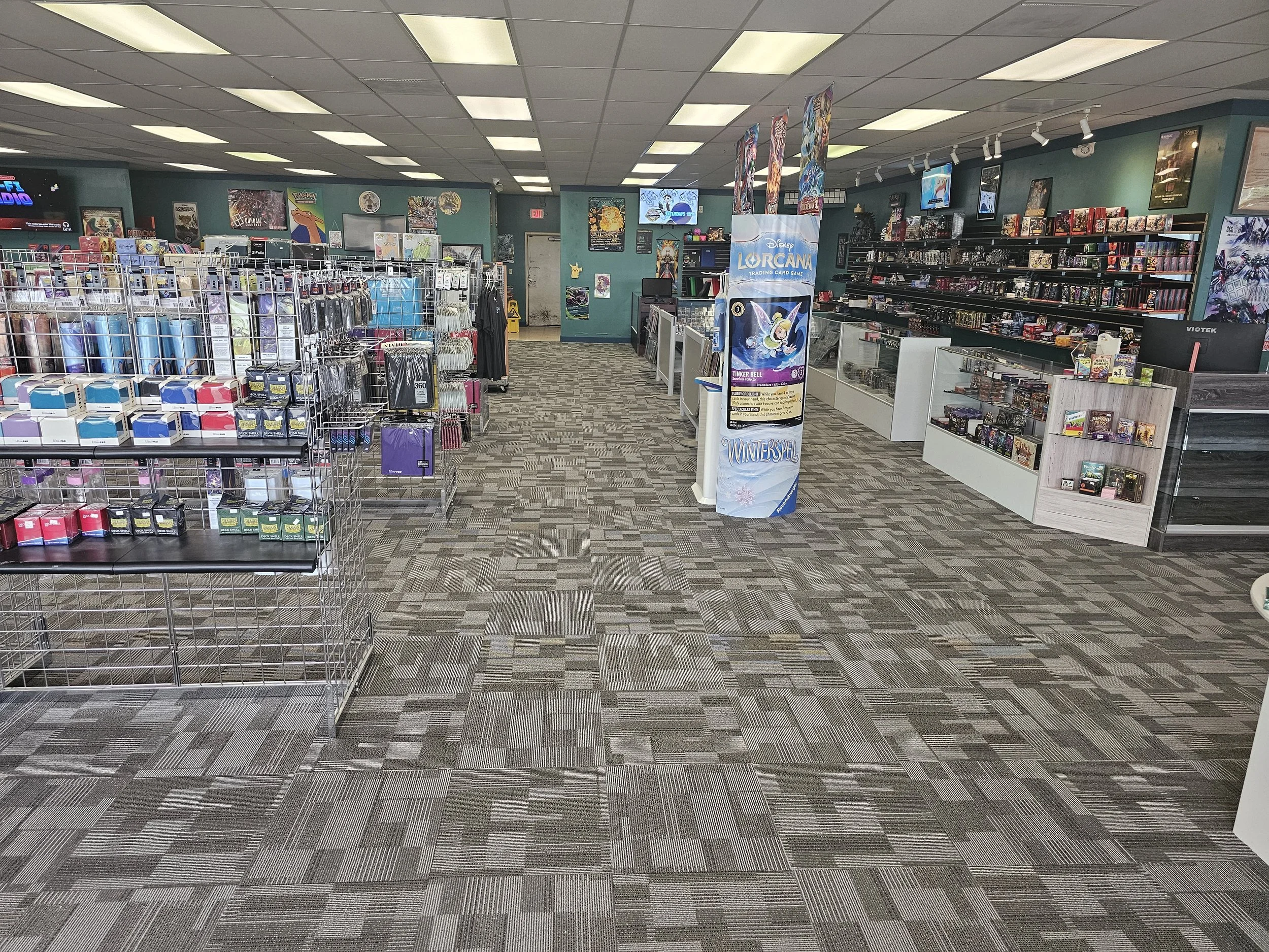 A retail store selling trading card games, figurines, and related merchandise, with shelves of products, promotional banners, and a cash register area.