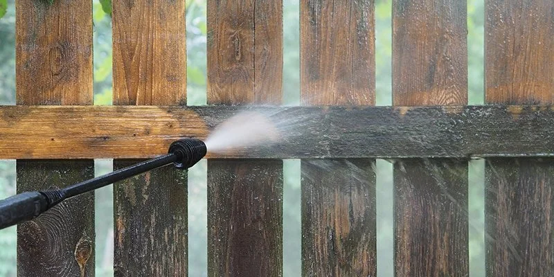 Power washer cleaning a wooden fence.