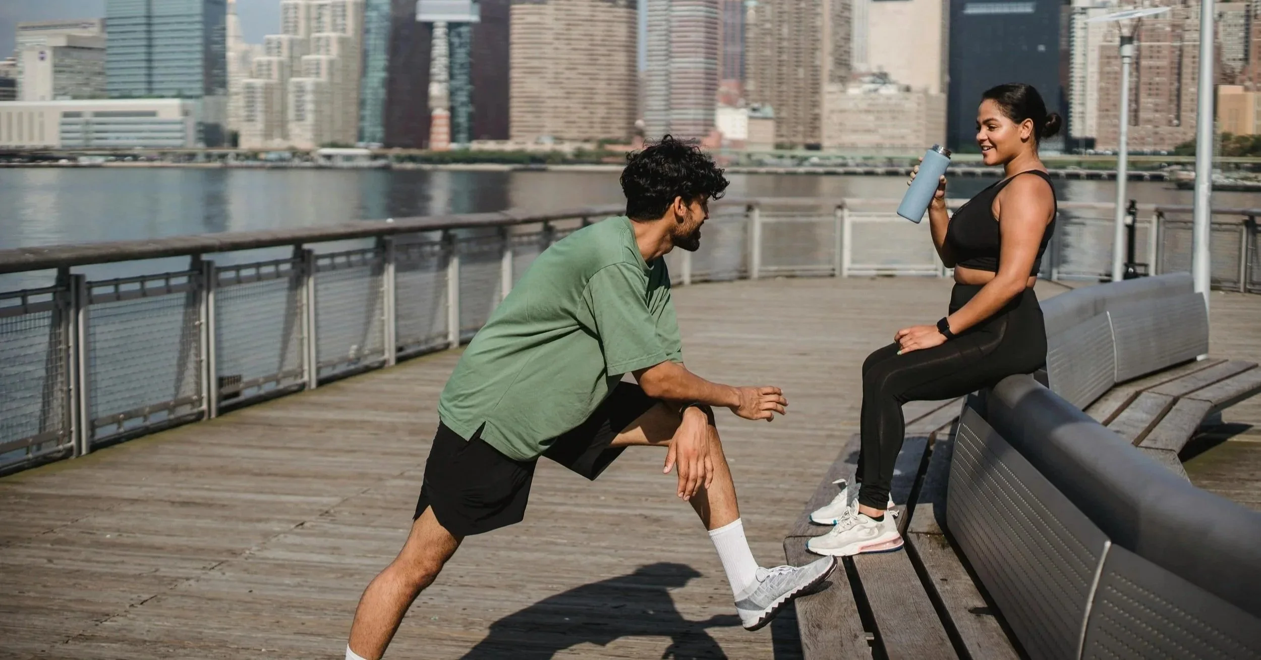 Couple jogging in the cityscape and talking on the docs by the water.