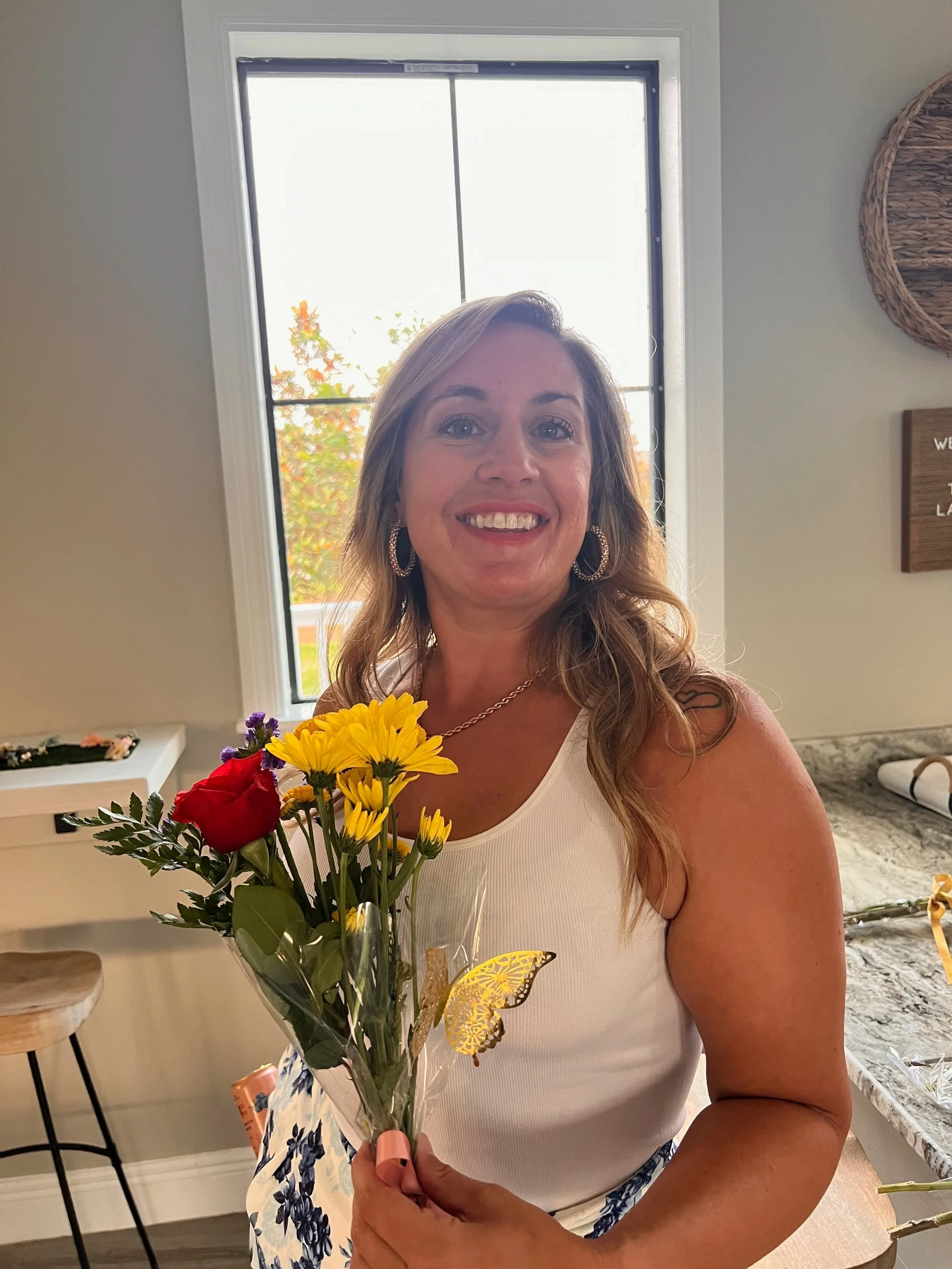 A woman smiling holding flowers.