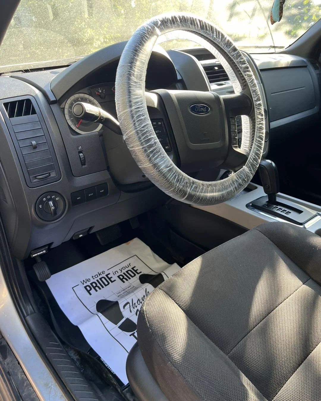 Person cleaning the dashboard of a car with a blue cloth inside the vehicle.