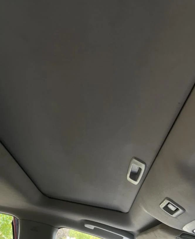 The interior ceiling of a vehicle with two interior lights and a closed sunroof.