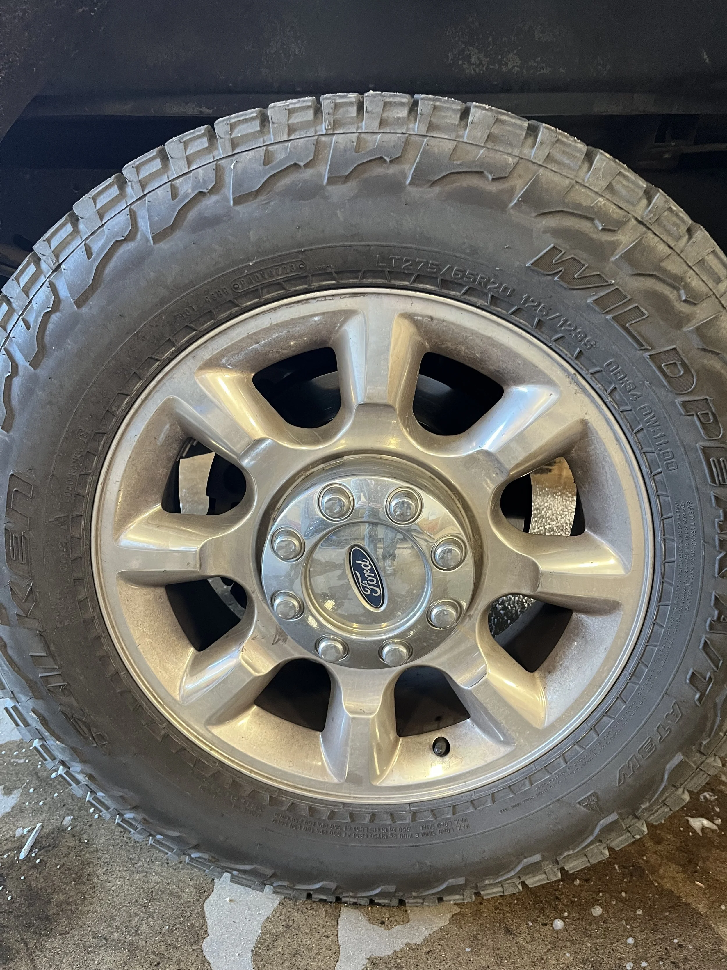 A close-up of a Ford vehicle wheel with alloy rim and a Wayne brand tire.