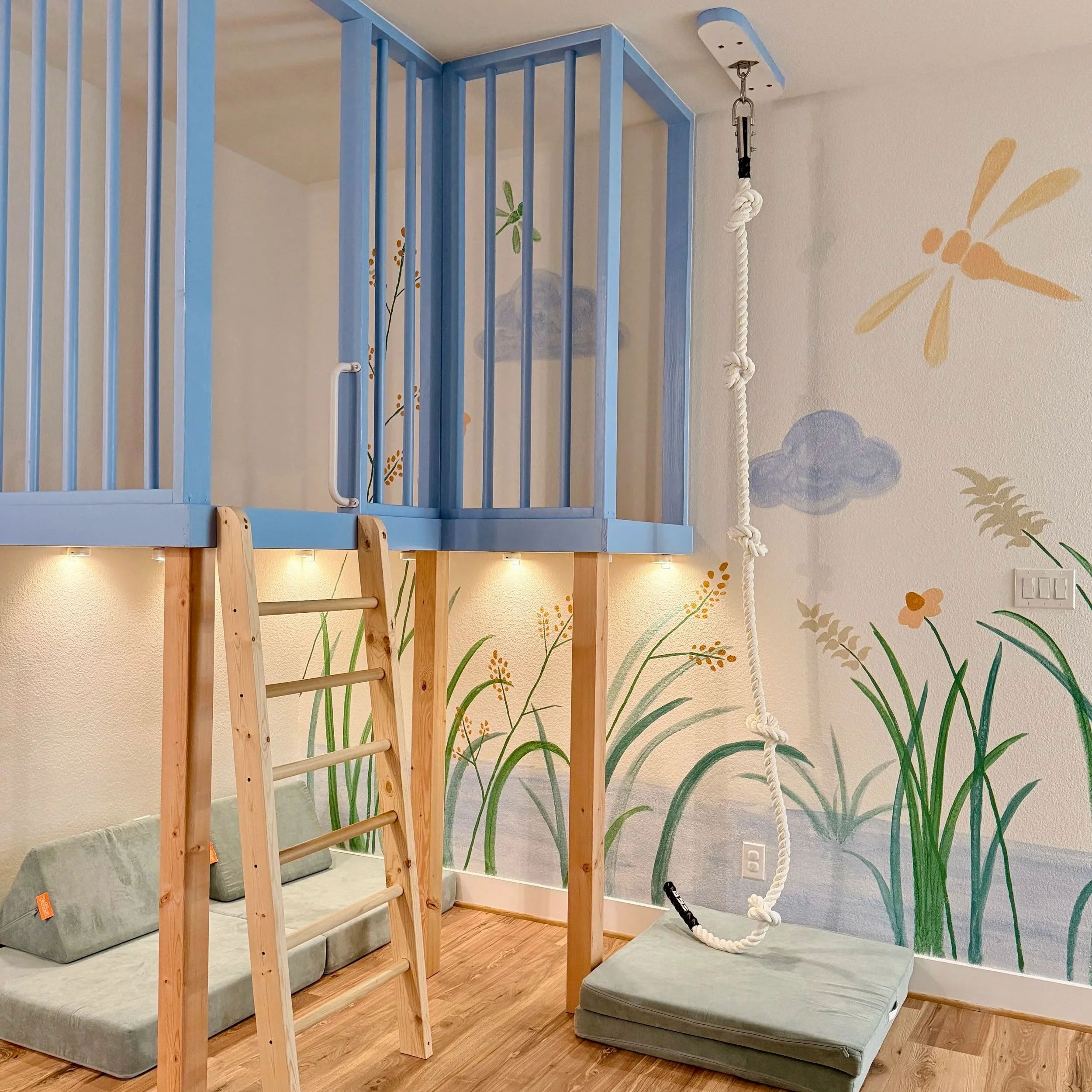 Blye platfrom with a birch ladder and whimsical mural of reeds and dragonfly in the background