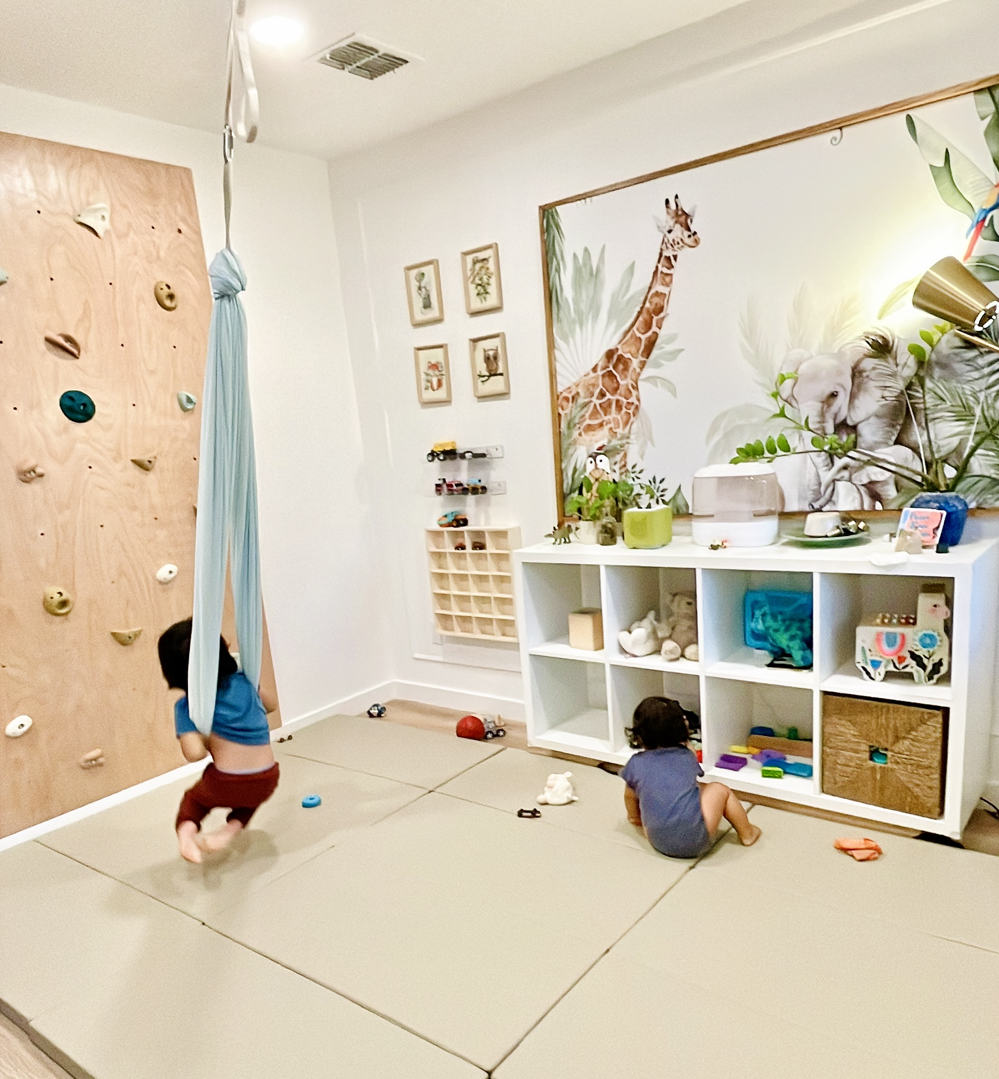 Toddler swinging while infant plays on floor