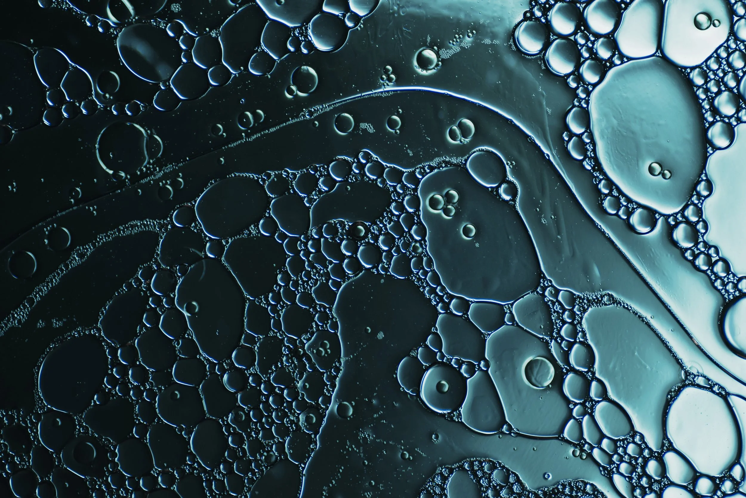 Macro photograph of water droplets and air bubbles forming intricate cellular patterns.