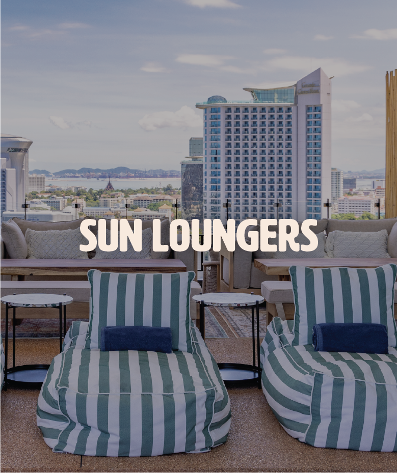 Indoor lounge area with striped bean bag chairs, small side tables, and a view of the city skyline and water through large windows. Text overlay reads 'Sun Loungers'.