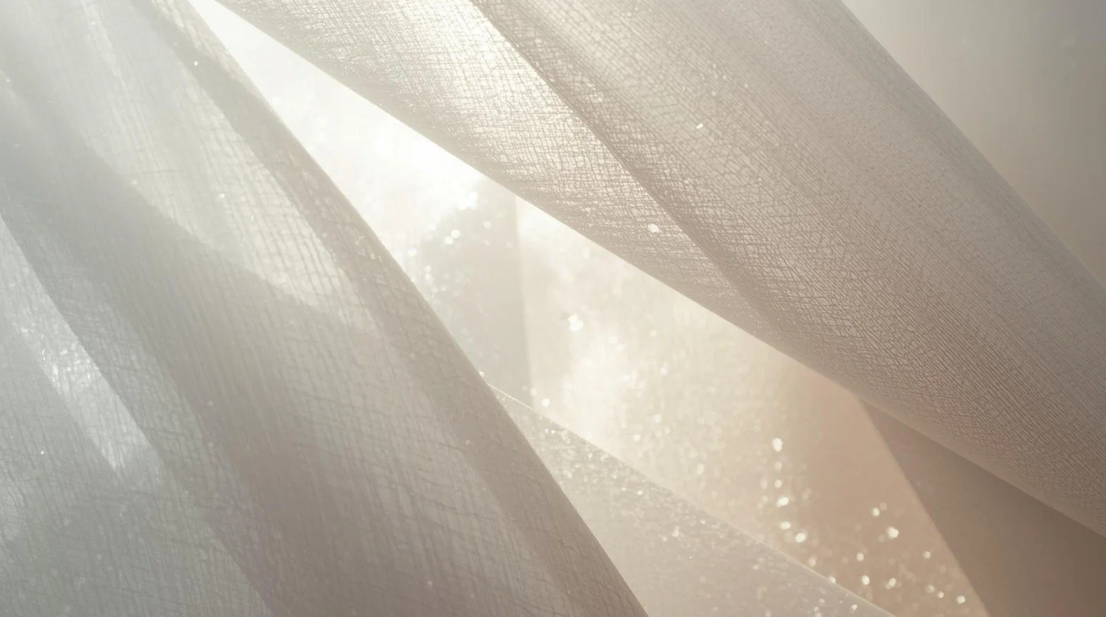 Close-up of sheer white curtains with sunlight filtering through.