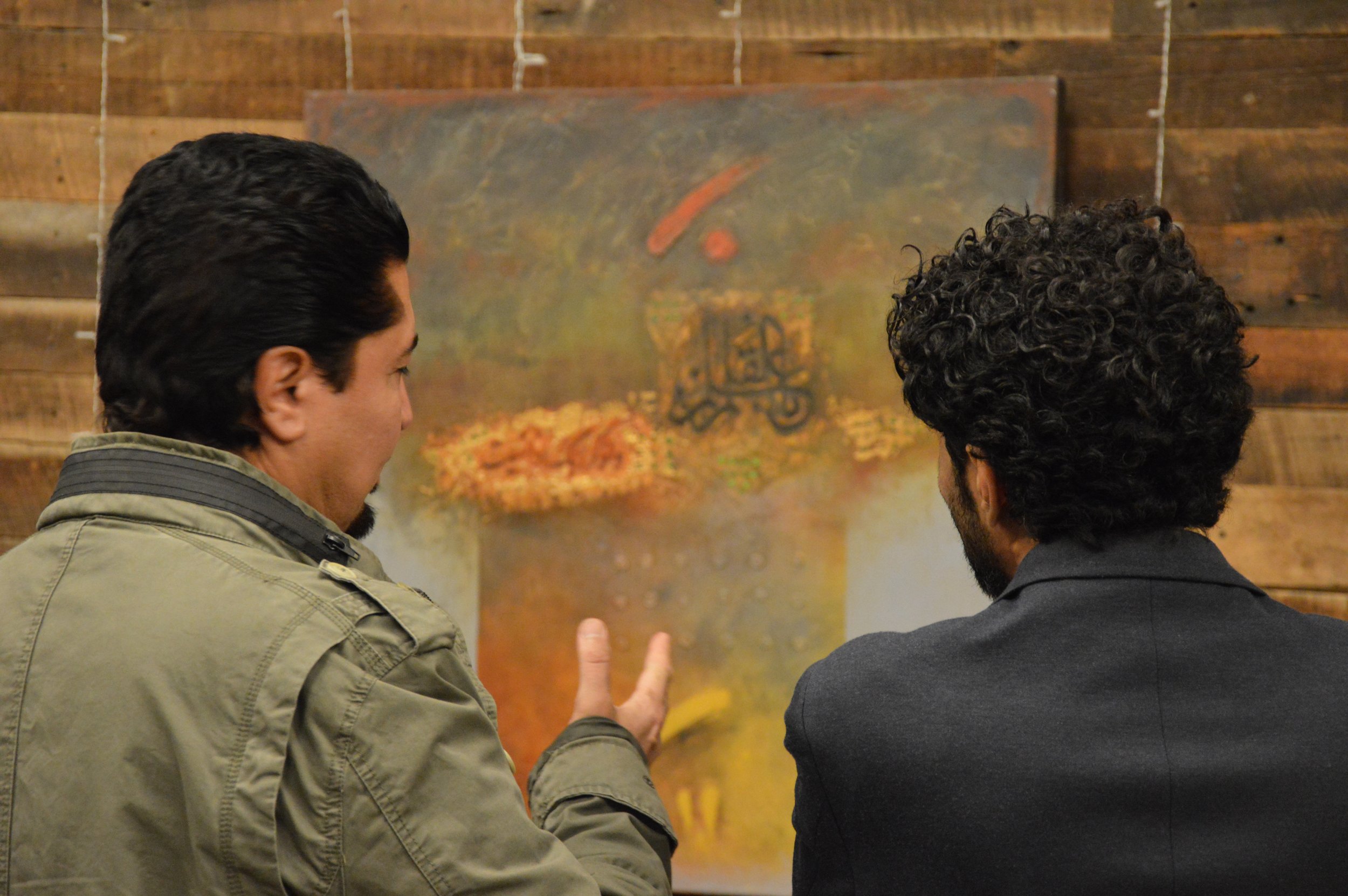 Iraqi artist Ahmed Alkarkhi from Maryland, USA explaining his artwork to an attendee of the Middle Eastern Arts Collective's inaugural art gallery in Alexandria, Virginia, USA showcasing Middle Eastern Arts from the DC Metro area.