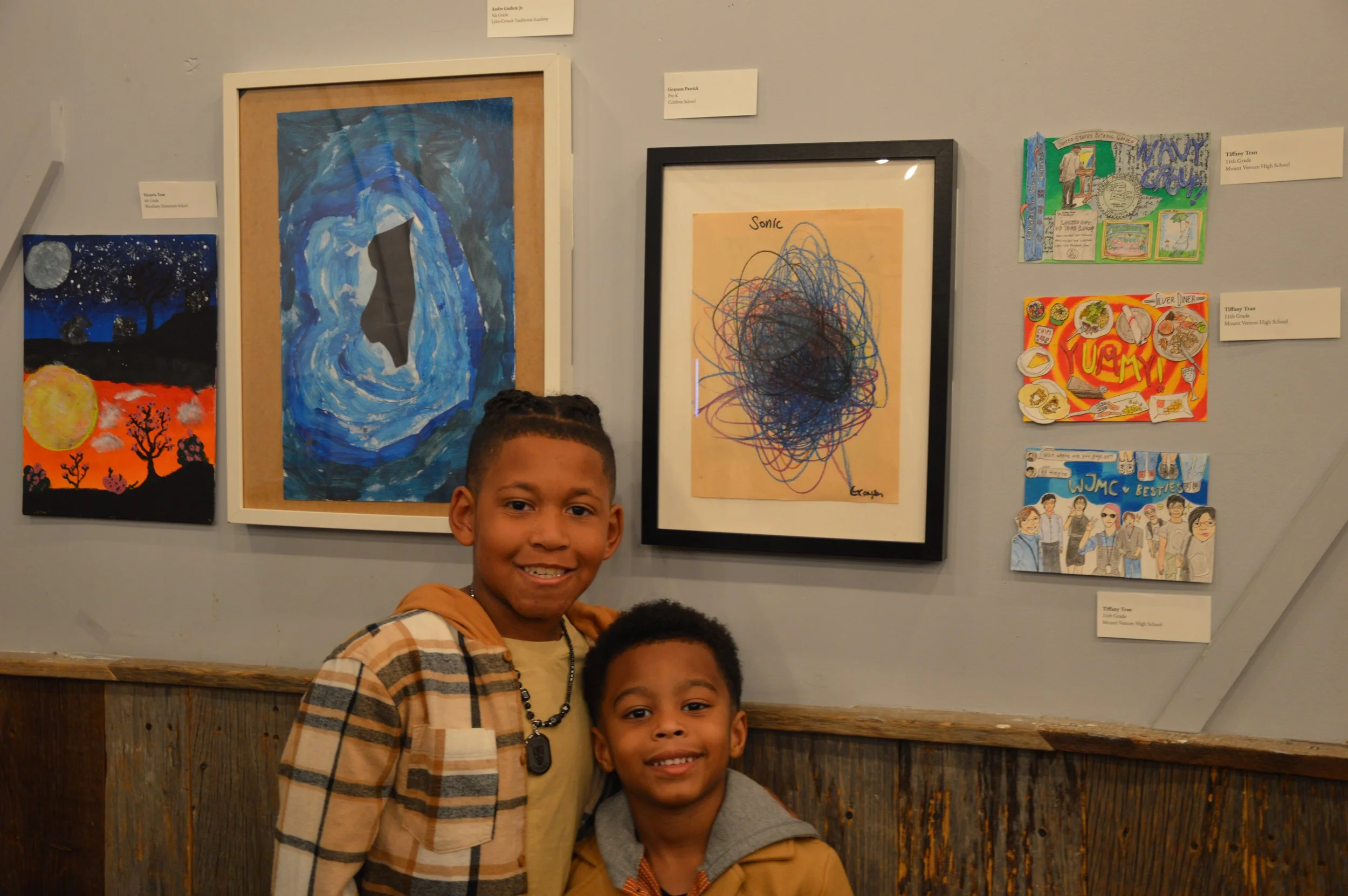 Two young boys in front of their artwork at the youth exhibit of the Middle Eastern Arts Collective's inaugural art gallery.