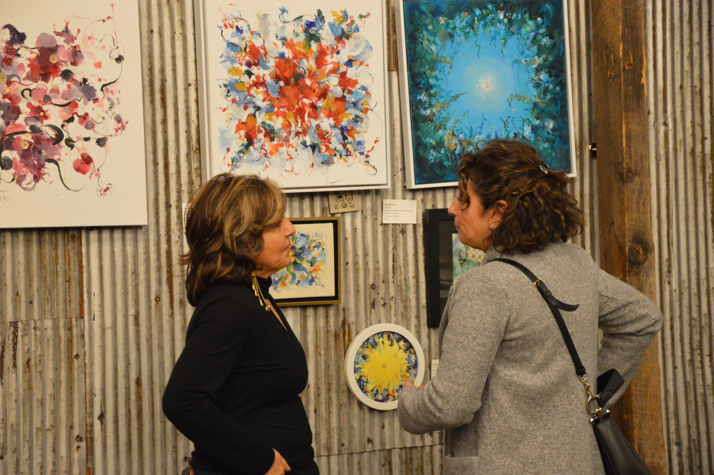 Iranian visual artist Saya Behnam explaining her paintings to an attendee of the Middle Eastern Arts Collective's inaugural art gallery in Alexandria, Virginia, USA.