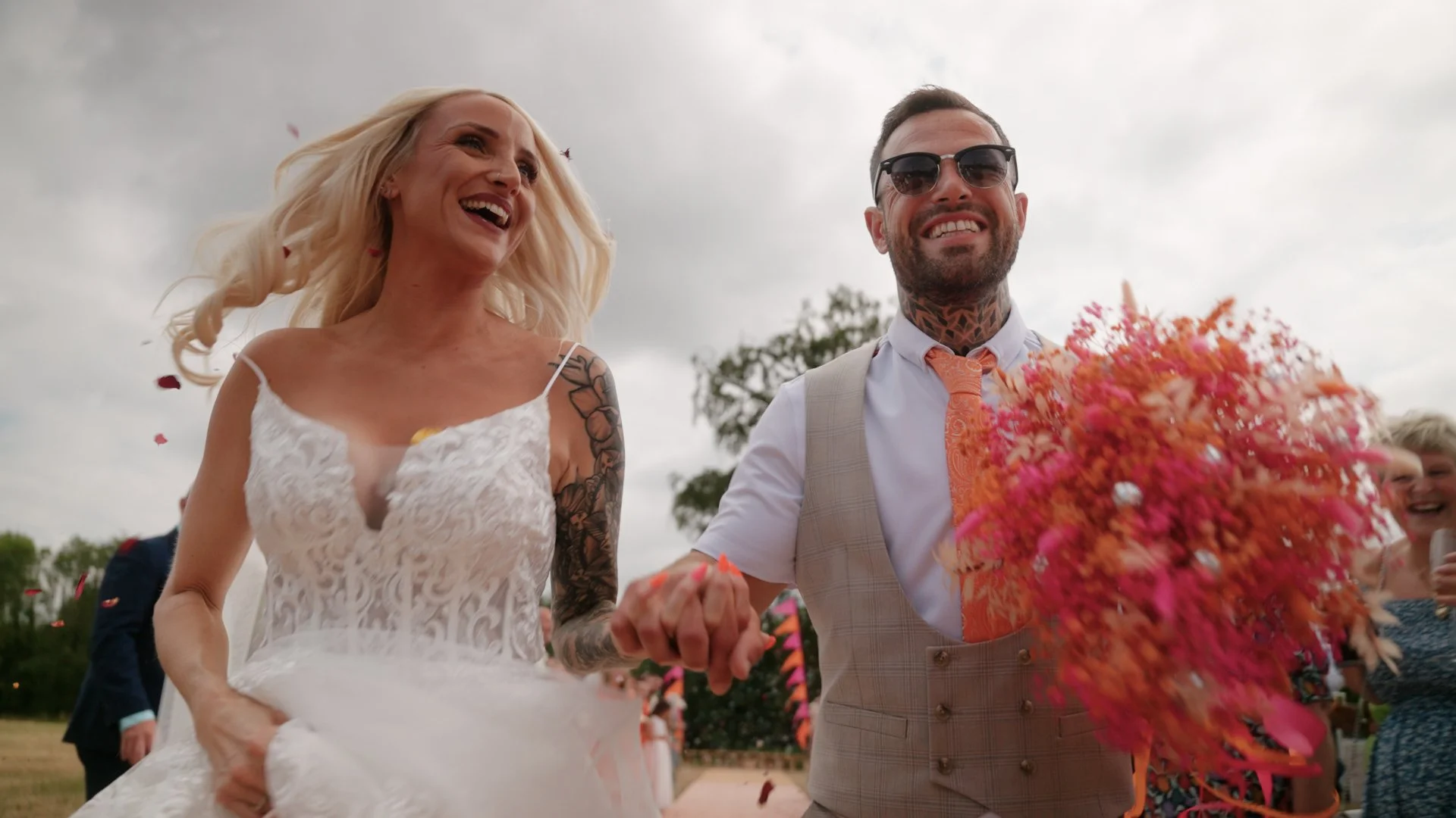 Husband and Wife holding hands running back down the aisle covered in confetti