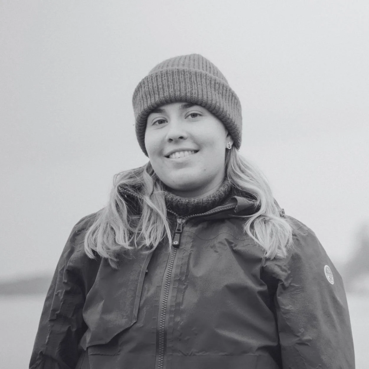 A woman smiling with water and land in the background