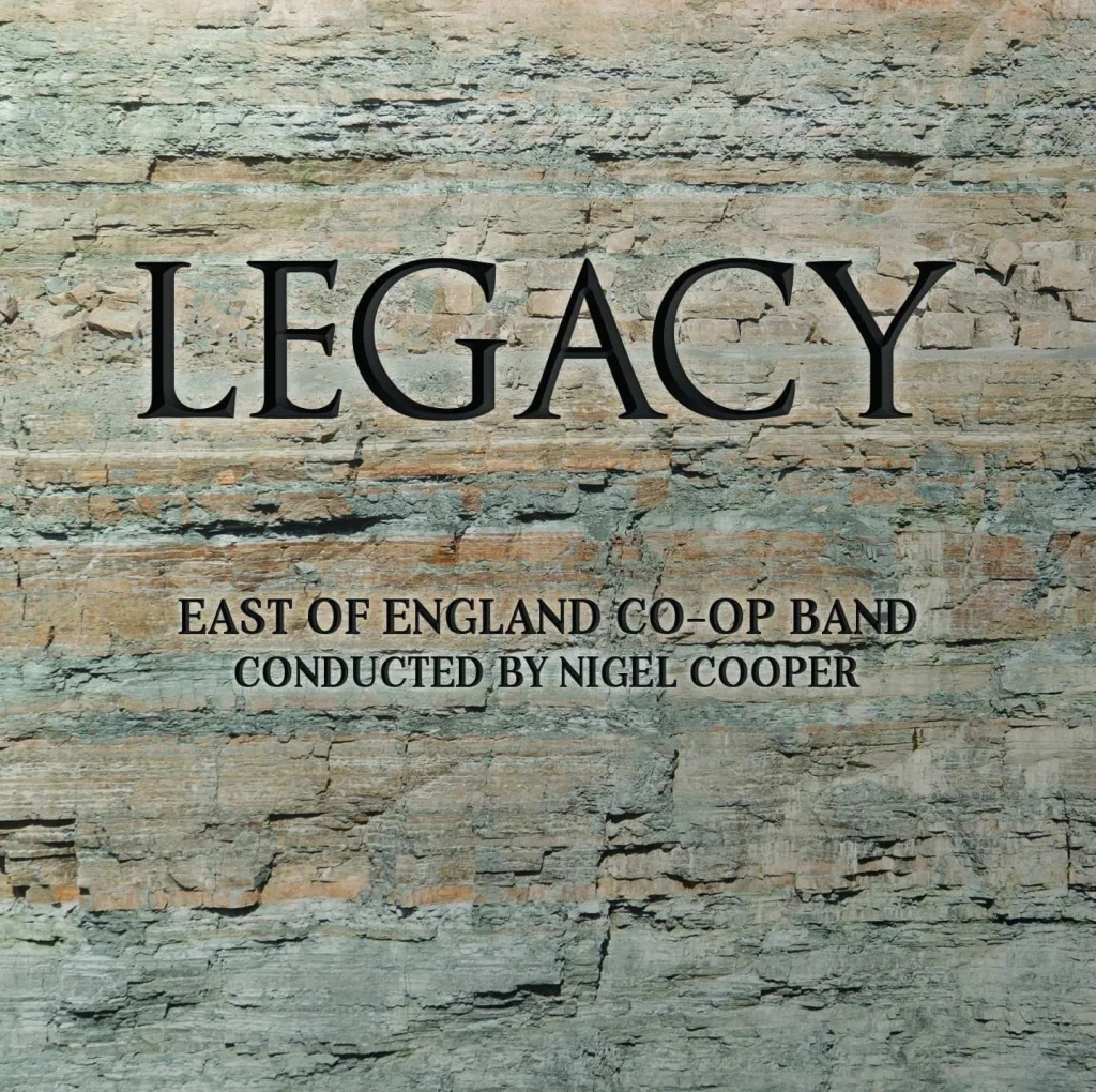 Sign on a stone wall that reads "LEGACY, EAST OF ENGLAND CO-OP BAND, CONDUCTED BY NIGEL COOPER".