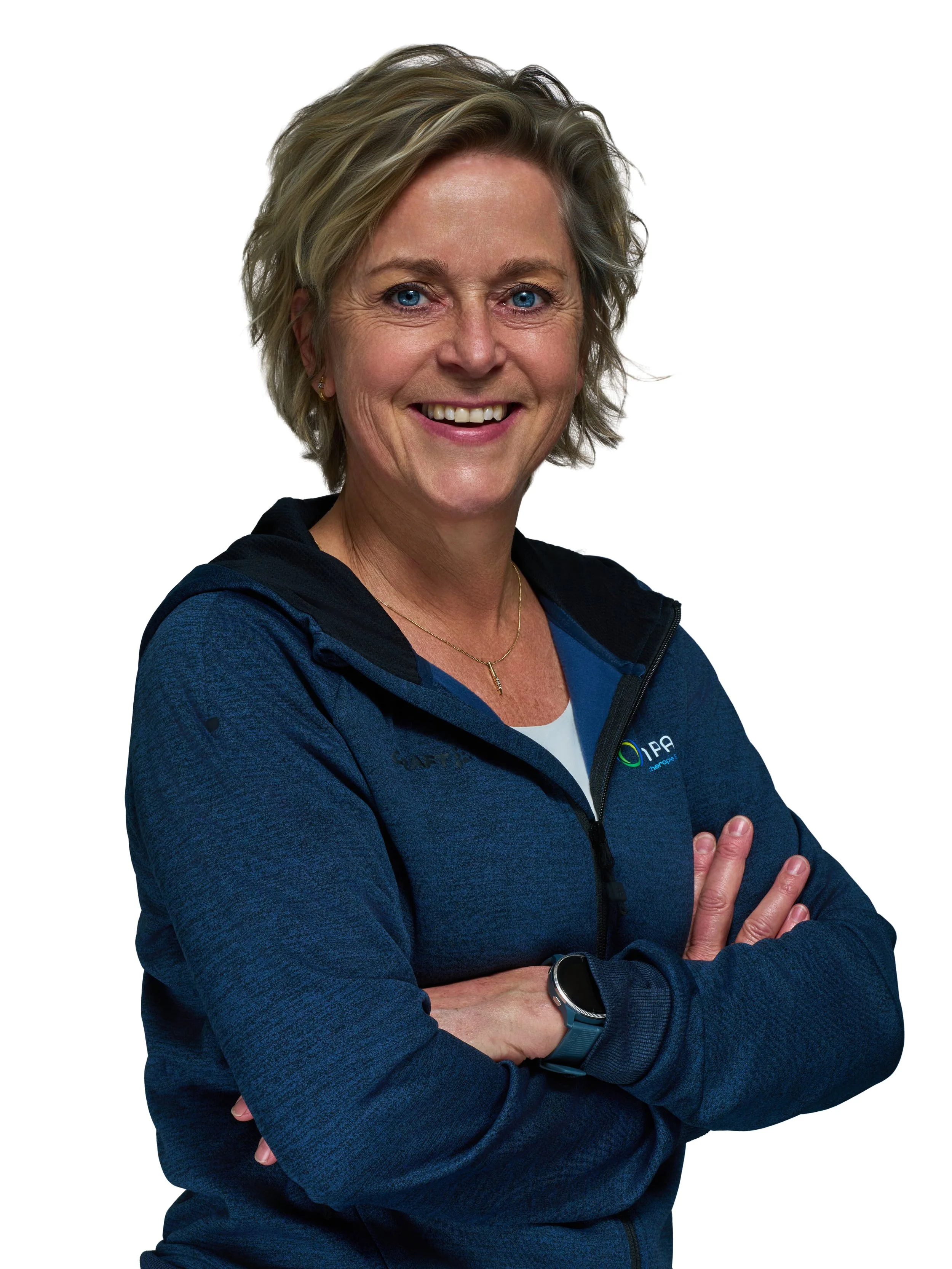 Portret van een lachende vrouw met kort blond haar, blauwe ogen, een blauwe sportjack en een smartwatch, met haar armen over elkaar