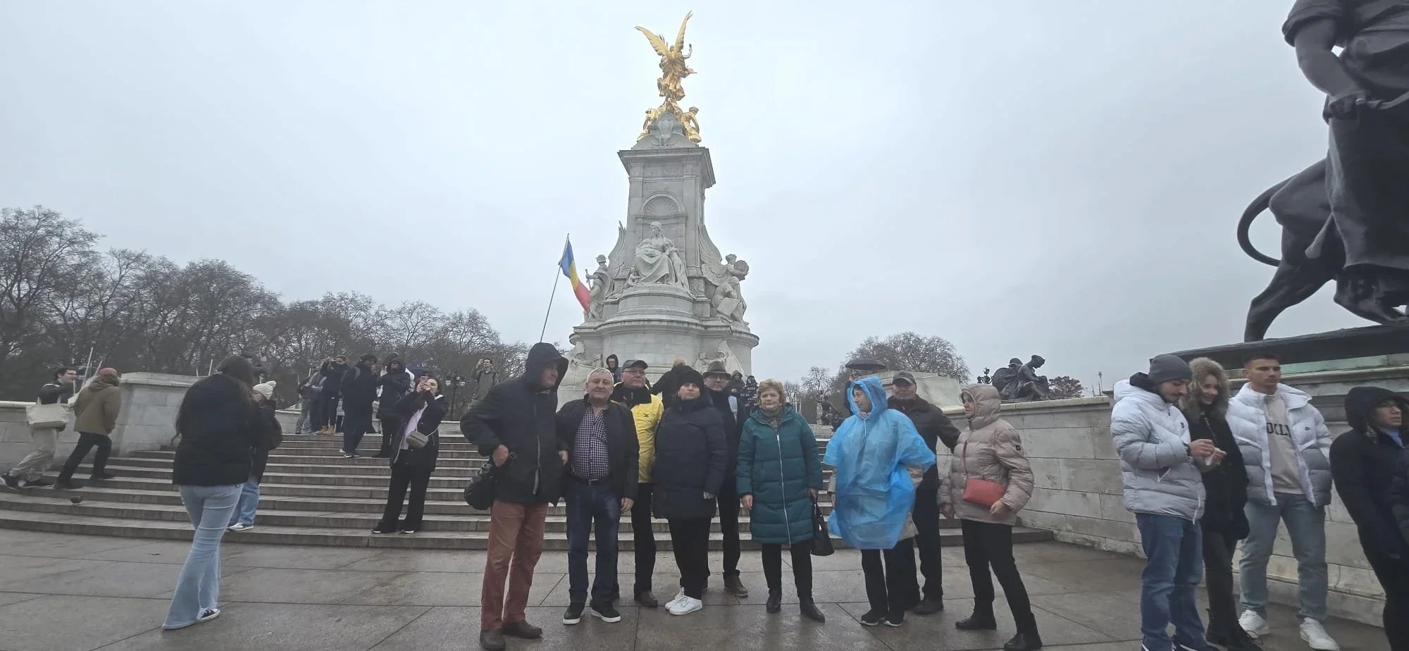 Group of tourists standing in front of the Alexander III monument in Paris, France, on a cloudy day.
