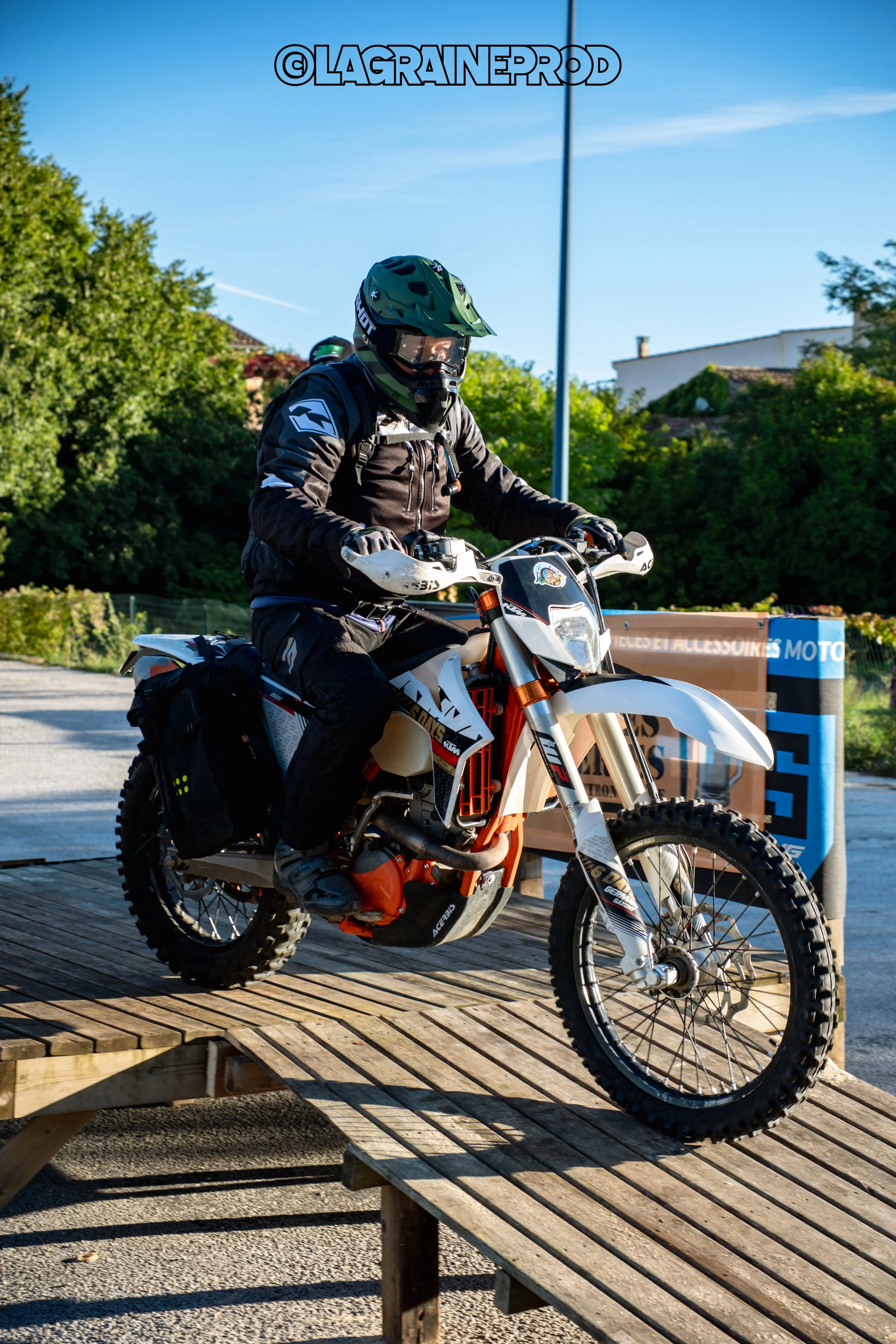 Motocycliste en tenue de protection sur une moto tout-terrain sur une rampe en bois