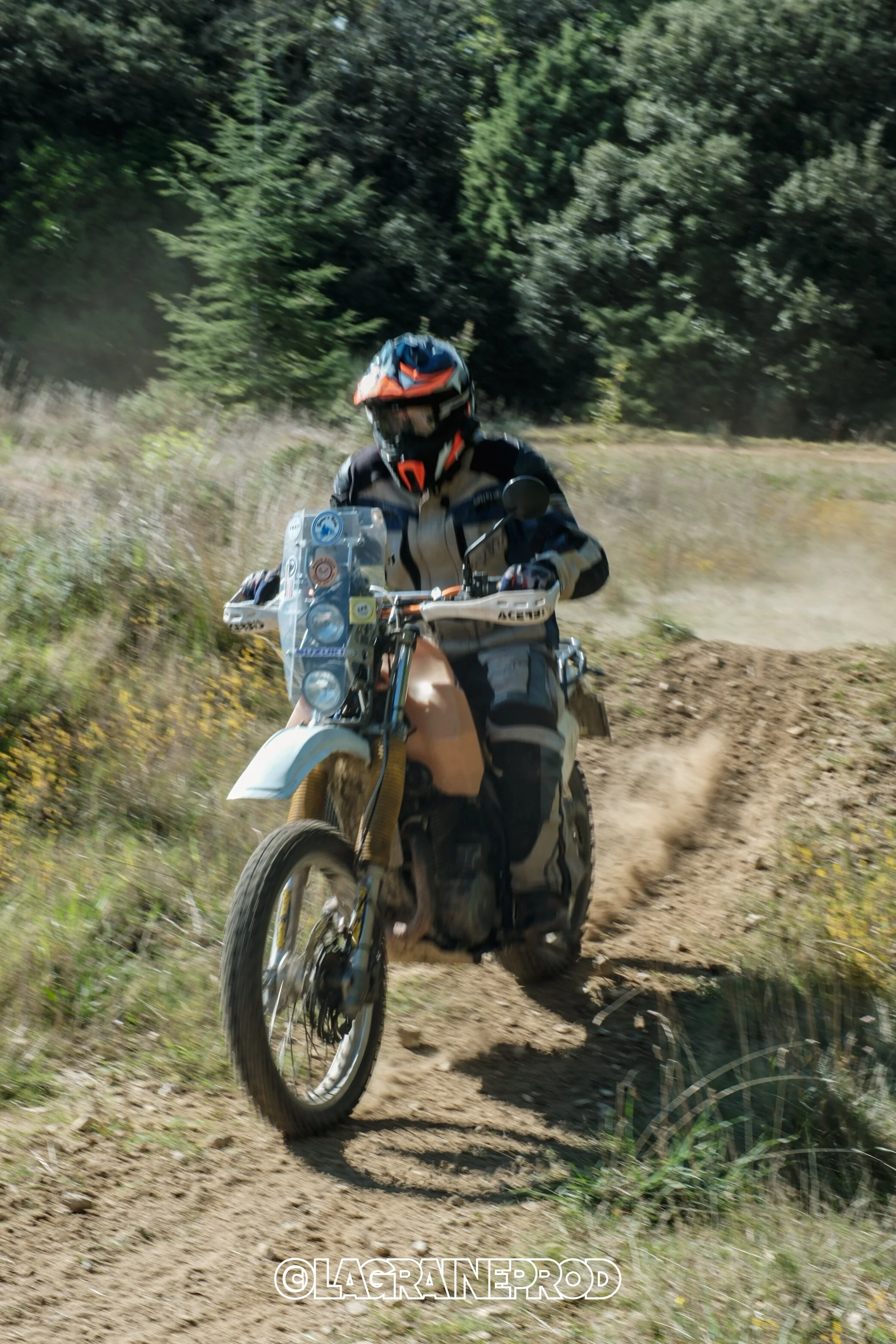 Motard en pleine action sur un sentier de dirt bike en pleine nature, portant un casque intégral et une tenue de protection.