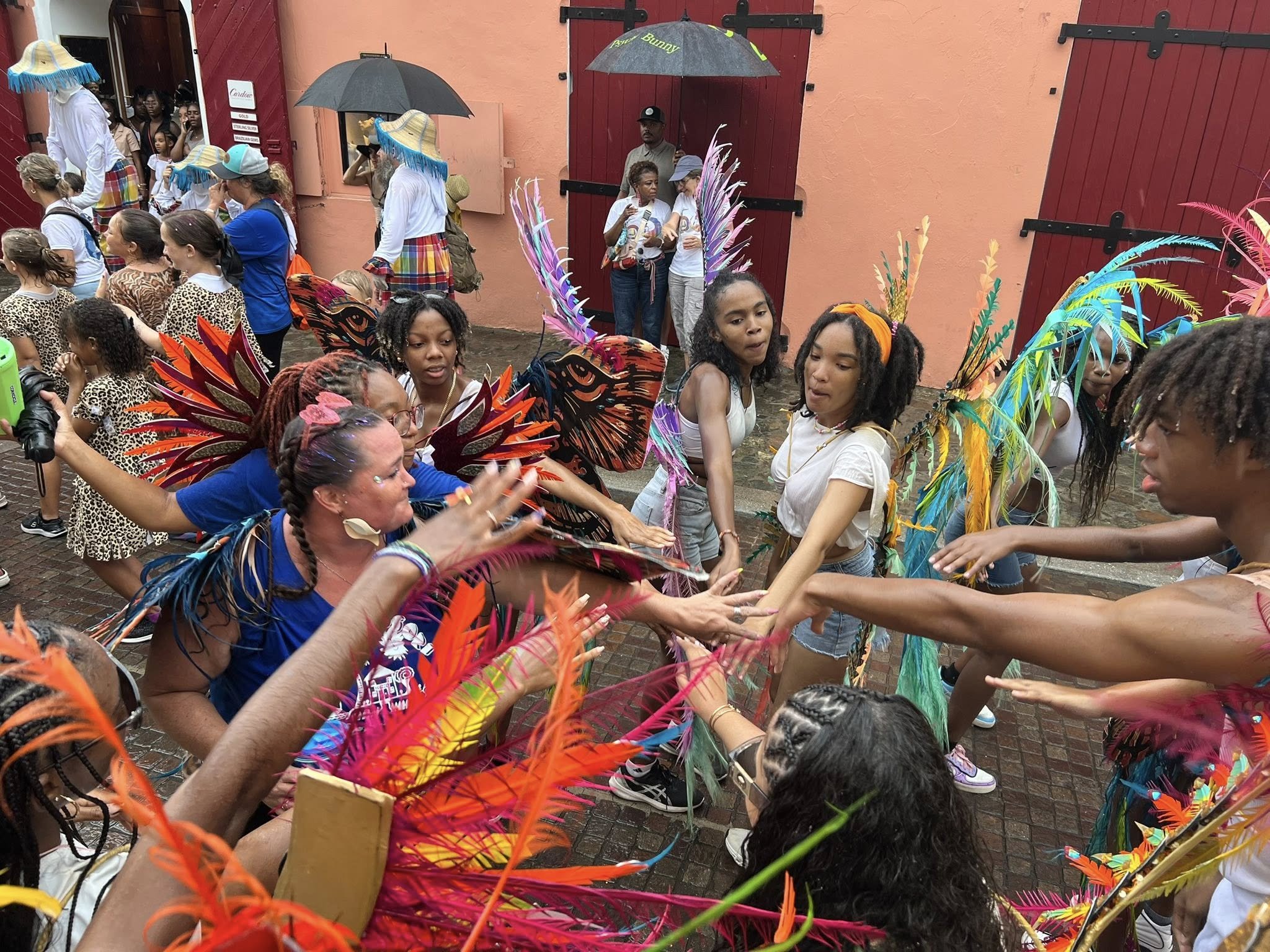 People dancing and celebrating in colorful costumes and feathered accessories at an outdoor event.