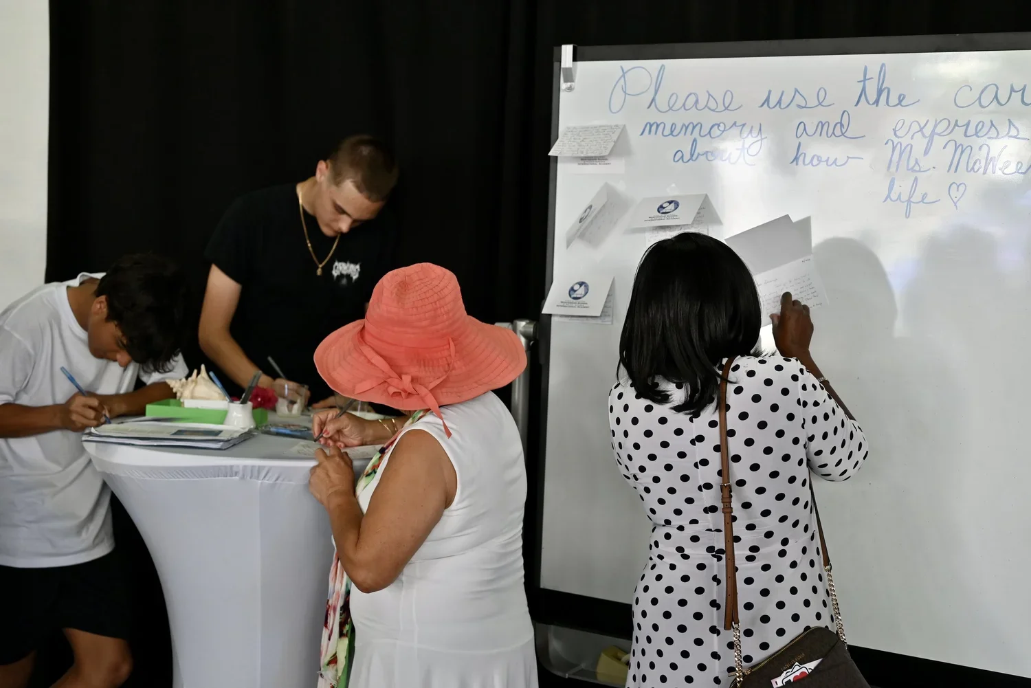 Group of people at a registration or informational event, with a whiteboard displaying a handwritten message about using a car memory.