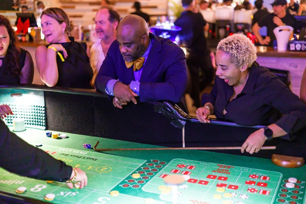 People playing and watching a game of craps at a casino table.