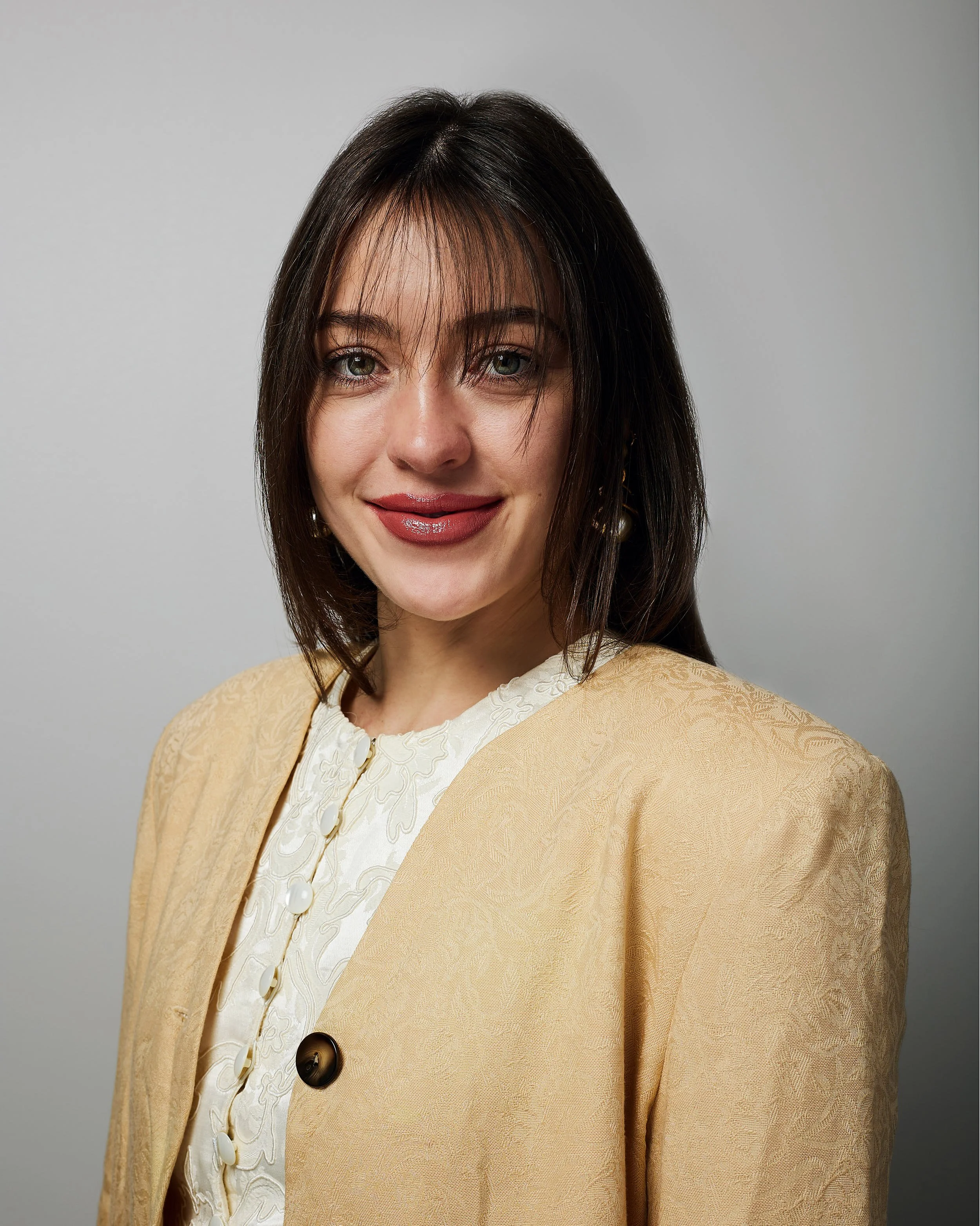 Headshot of young woman wearing a tan jacket.