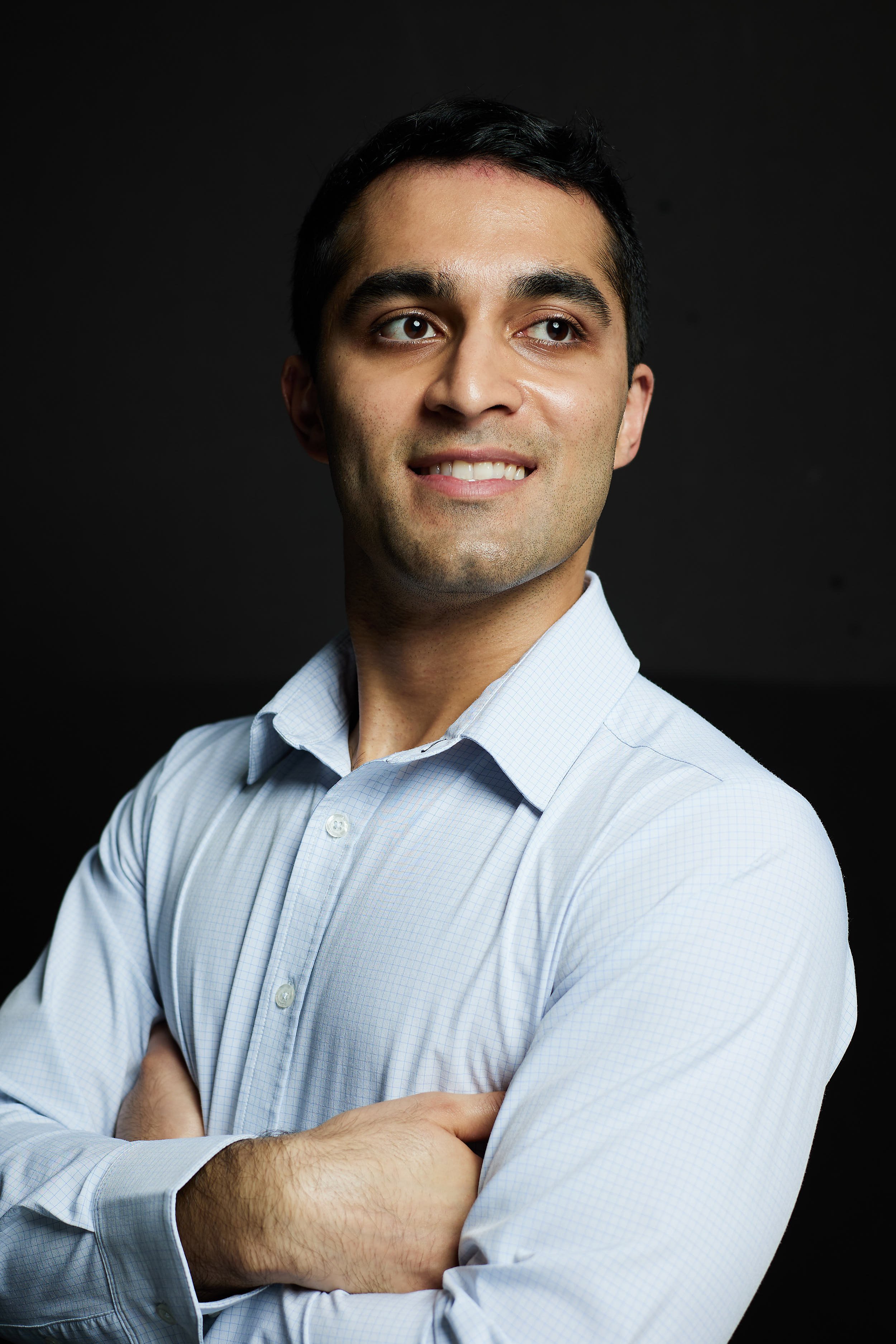 Portrait of young man with arms crossed wearing a light blue shirt.