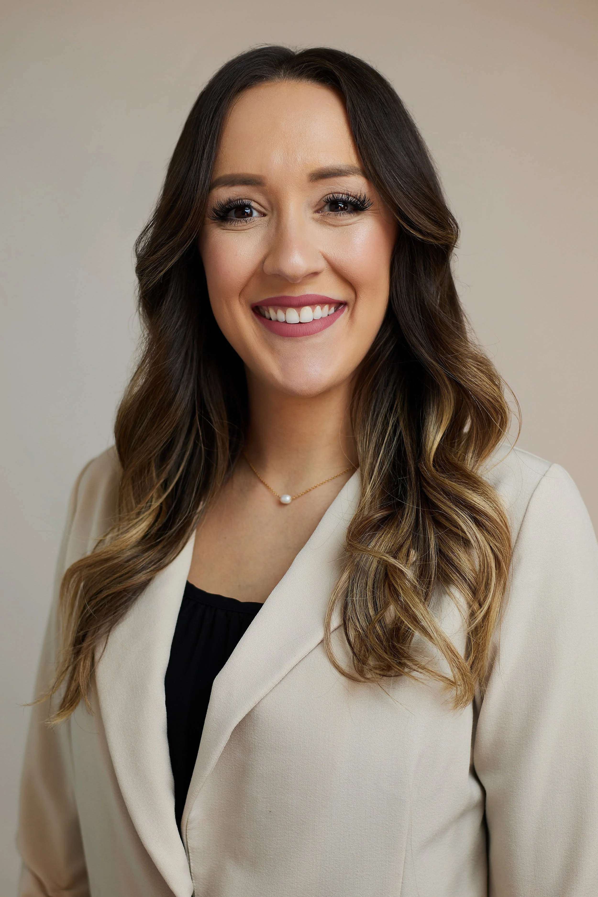 Headshot of woman with long dark hair wearing a cream jacket.