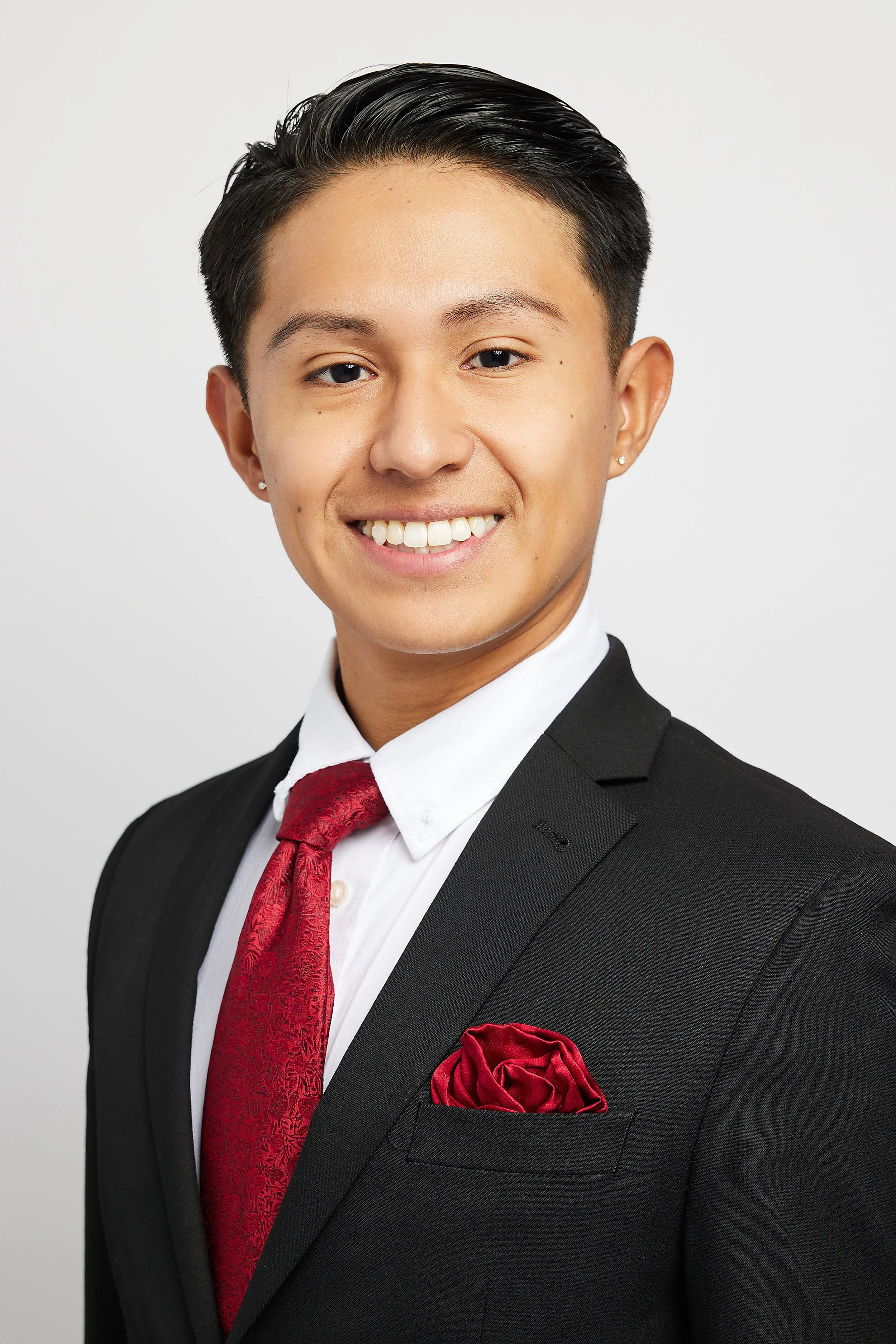 Headshot of young man wearing red tie smiling at camera.