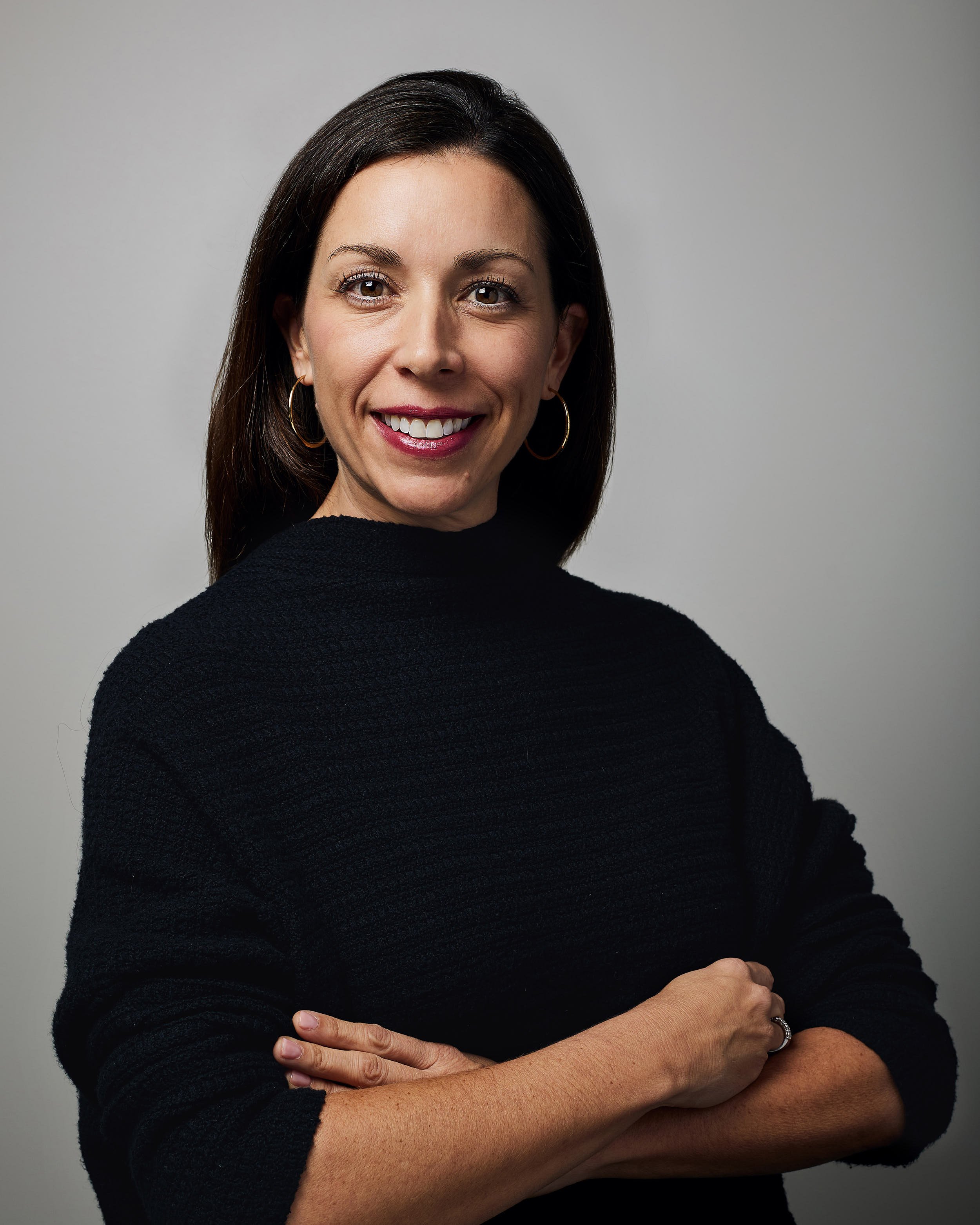 Studio portrait of woman CEO in black sweater with arms crossed.