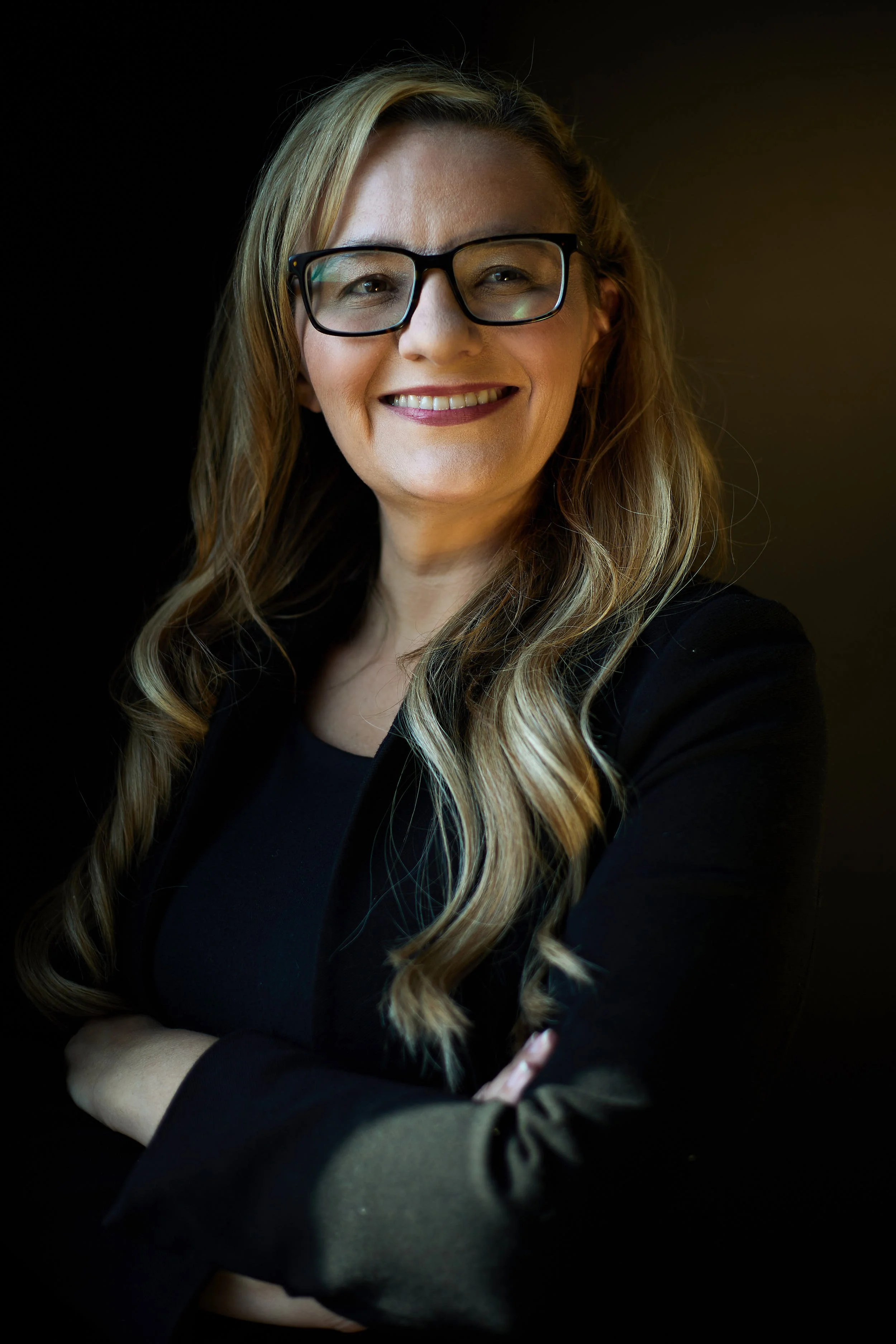 Portrait of CEO with arms crossed on dark background.