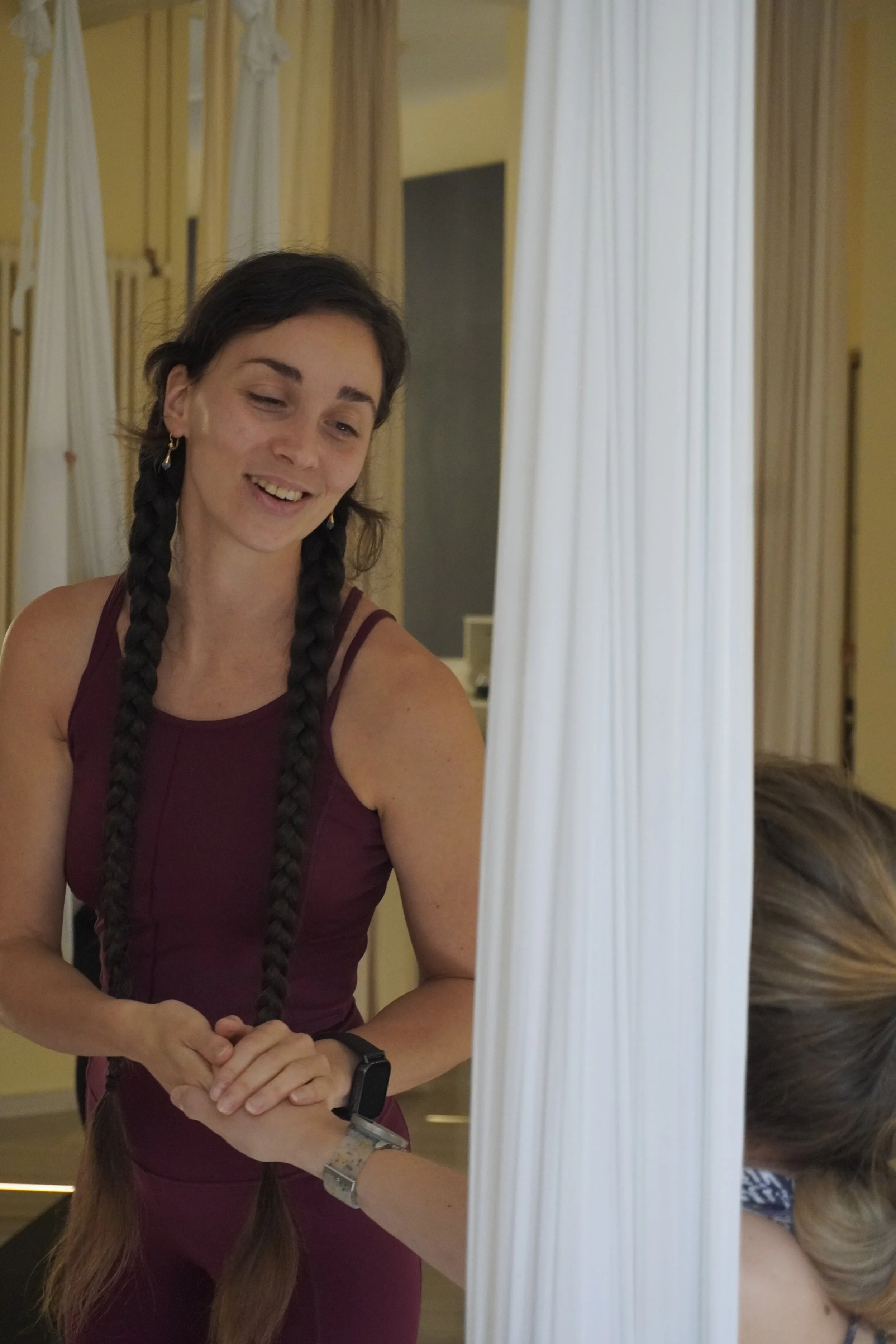 Insegnante di California Yoga che saluta uno studente che pratica aerial yoga