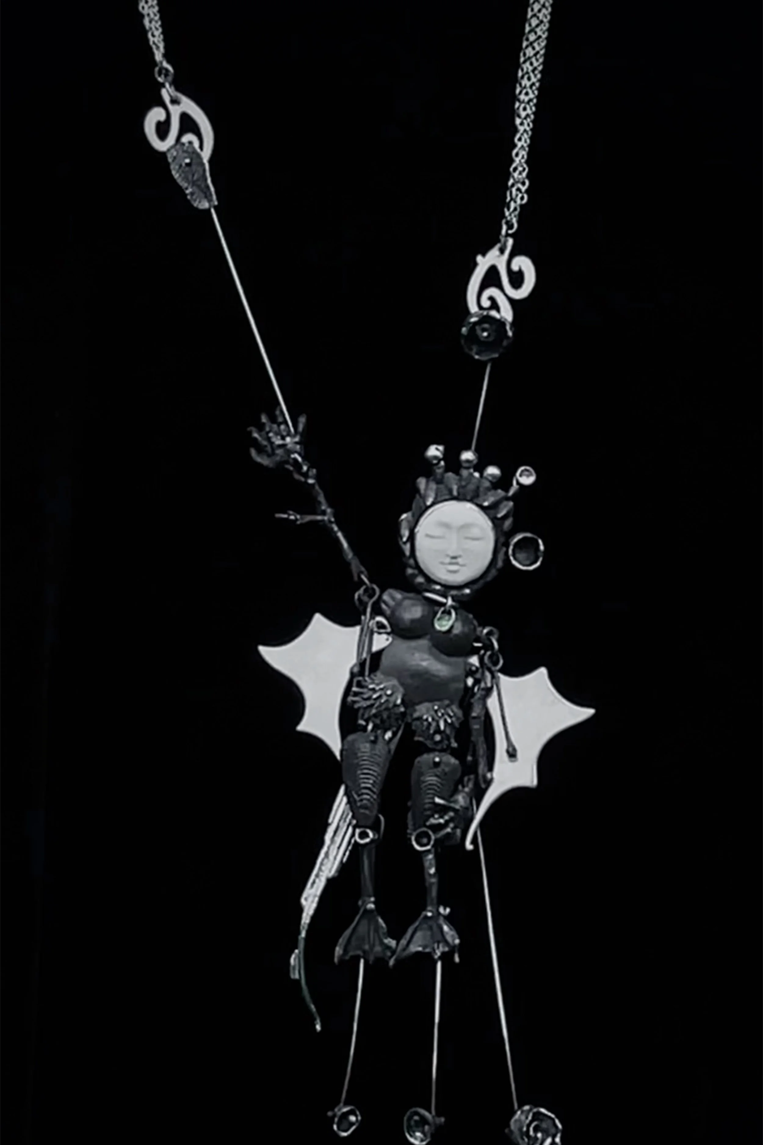 a silver doll puppet marionette necklace made with various casting techniques, she flaps her wings when you pull her tail.
