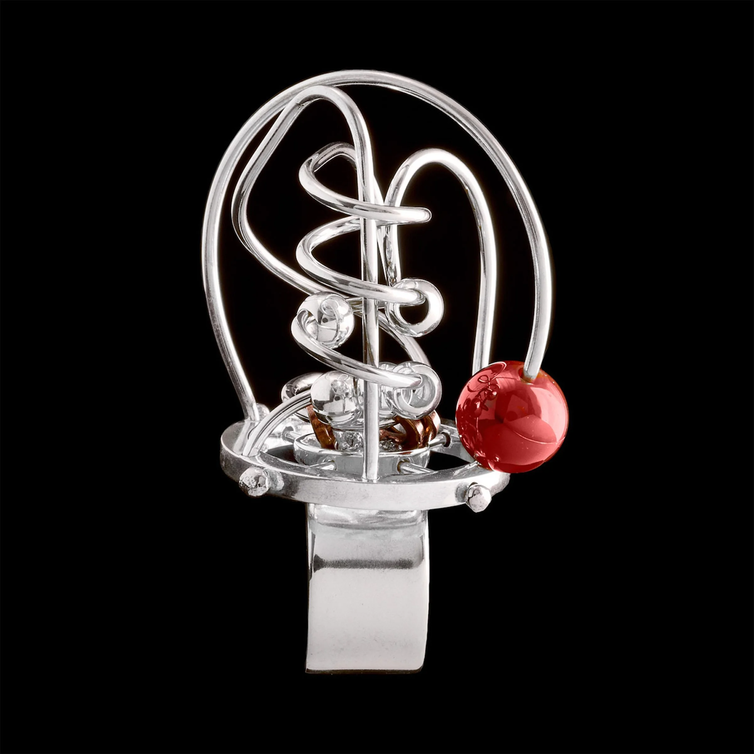 A silver ring with a miniature labyrinth maze and a carnelian bead at the entrance.
