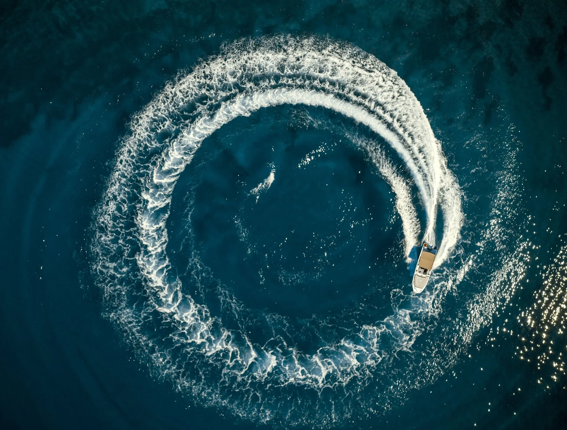 A boat moving in circles on the water, creating a spiral wake pattern.