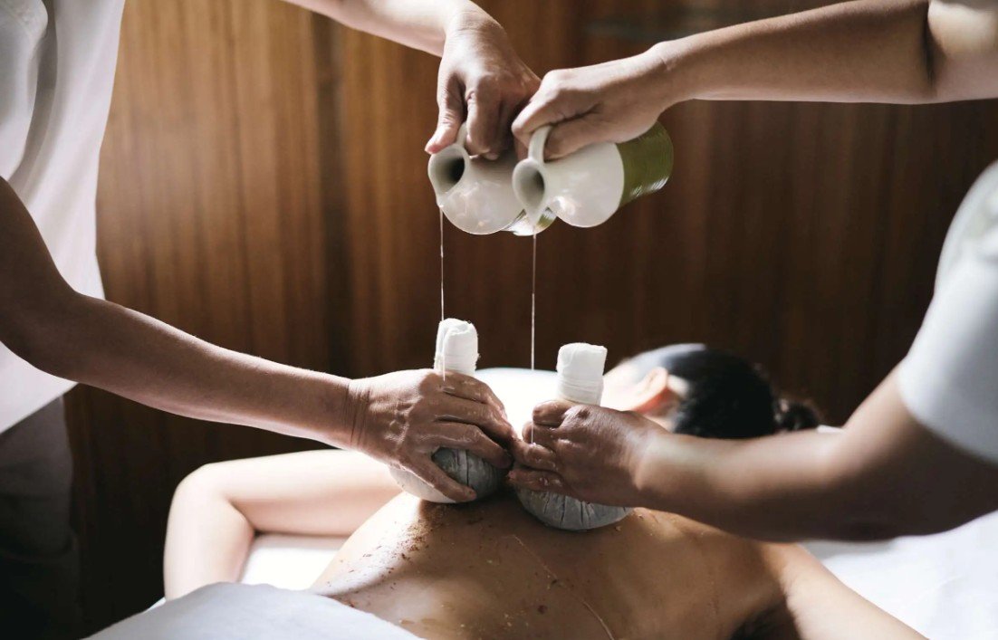 Two massage therapists applying hot stones to a person's back during a massage.